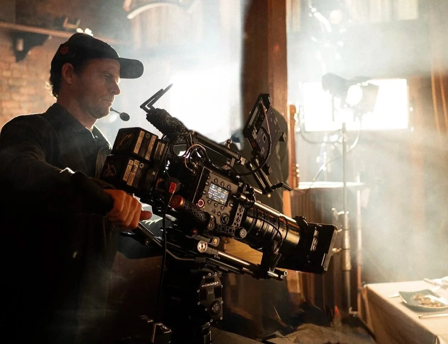 Joey Arcisz operating a cinema camera on a haze-lit interior set