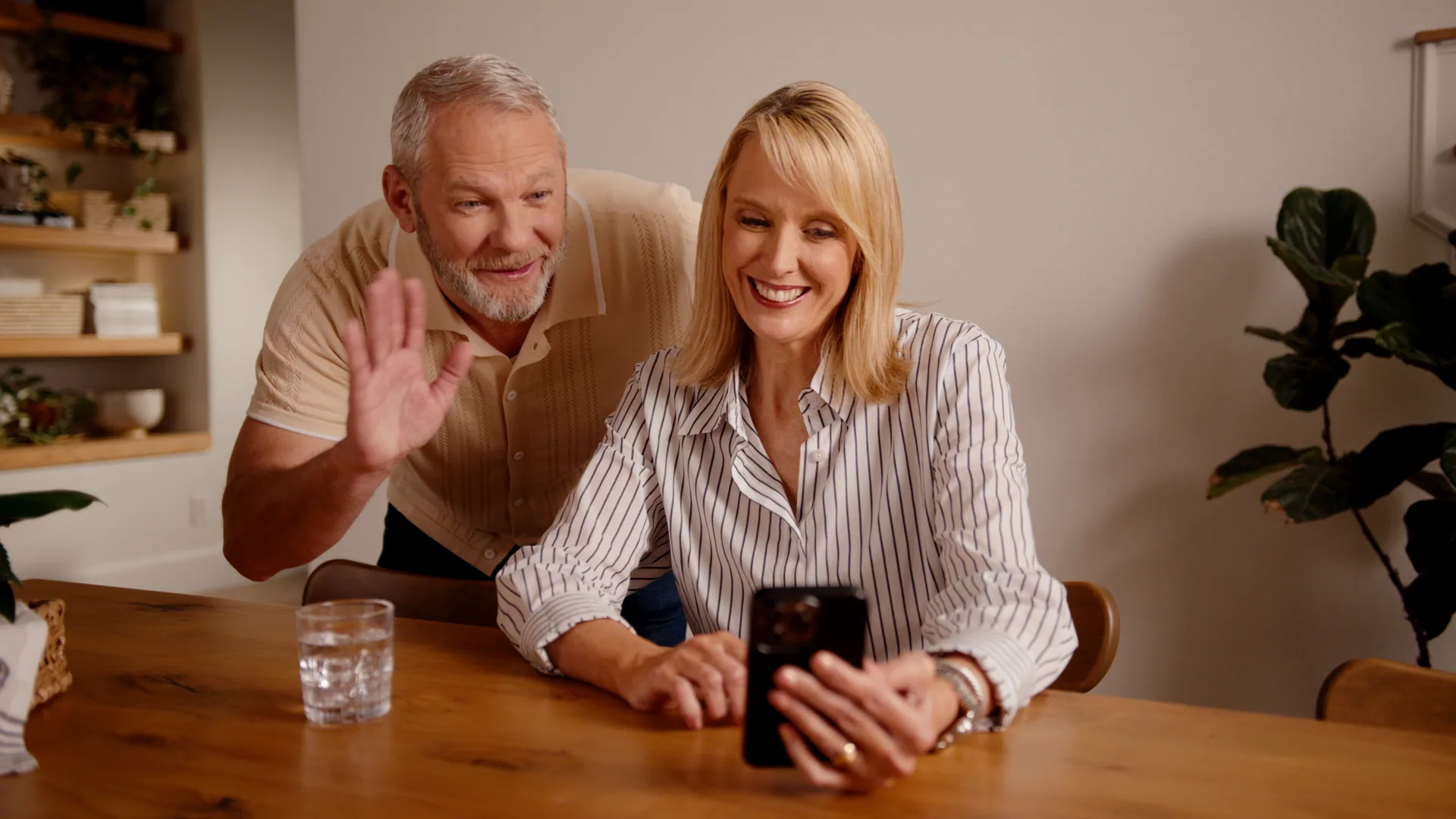 Delivered frame of a couple at the Olivia dining table waving at a video call