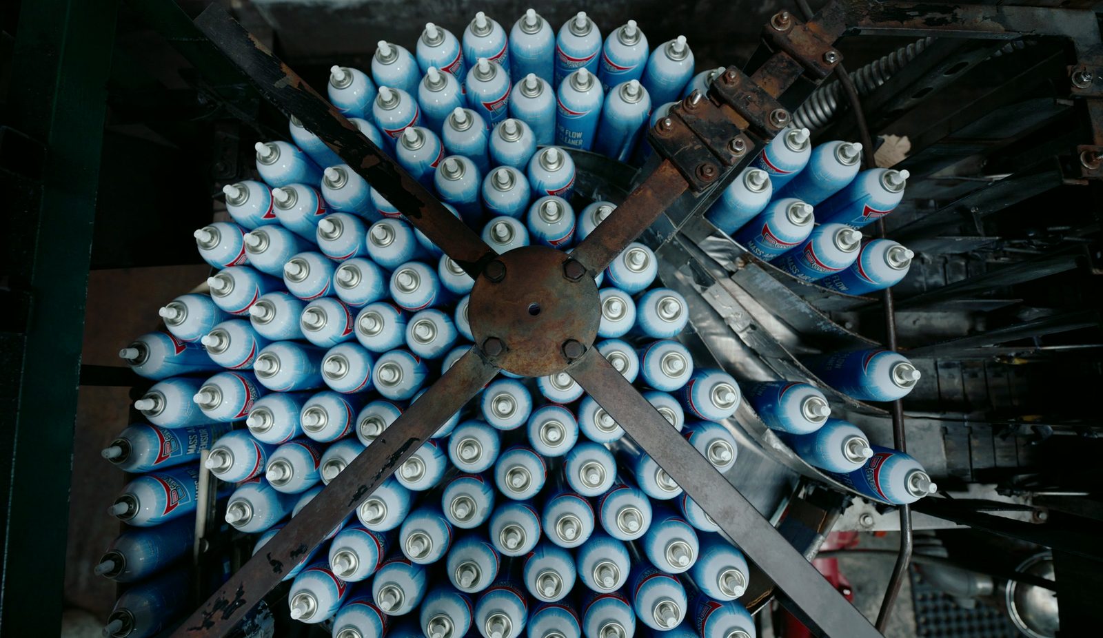 Overhead view of spray cans arranged in a radial pattern on factory machinery.