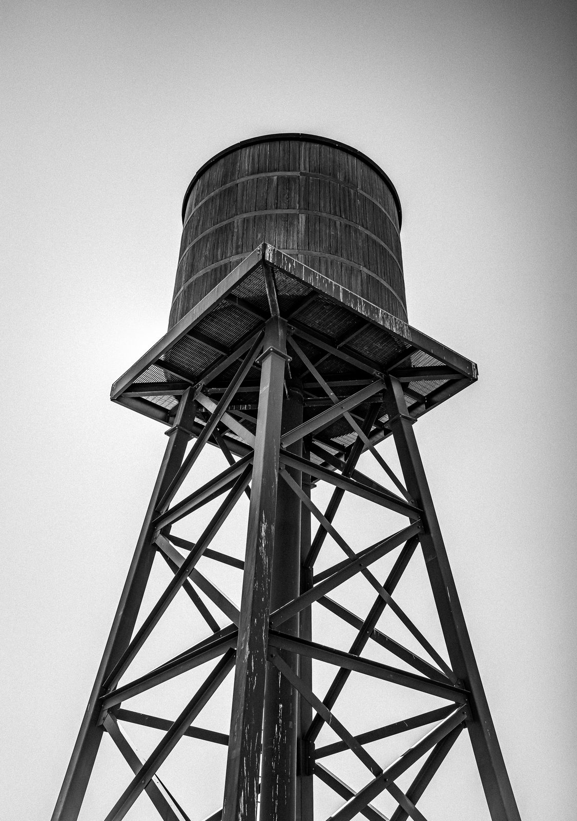 Black and white photo looking up at a steel desert water tower against a pale sky.