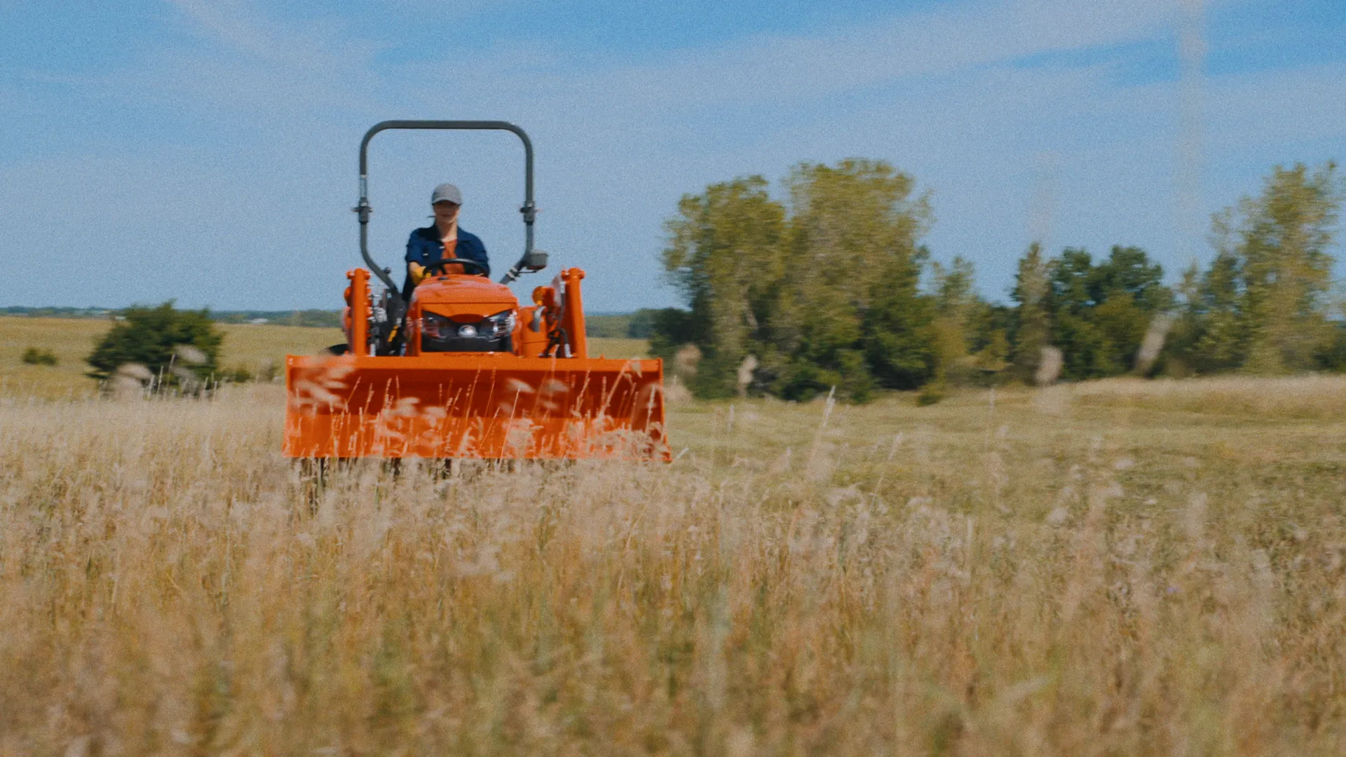Kubota tractor head-on through tall golden grass