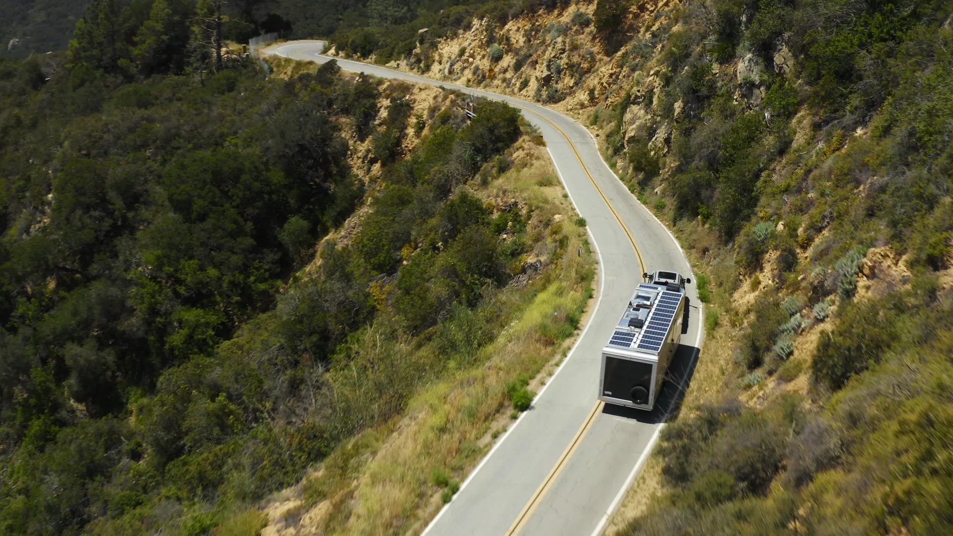 Drone chasing a Living Vehicle trailer down a winding mountain road
