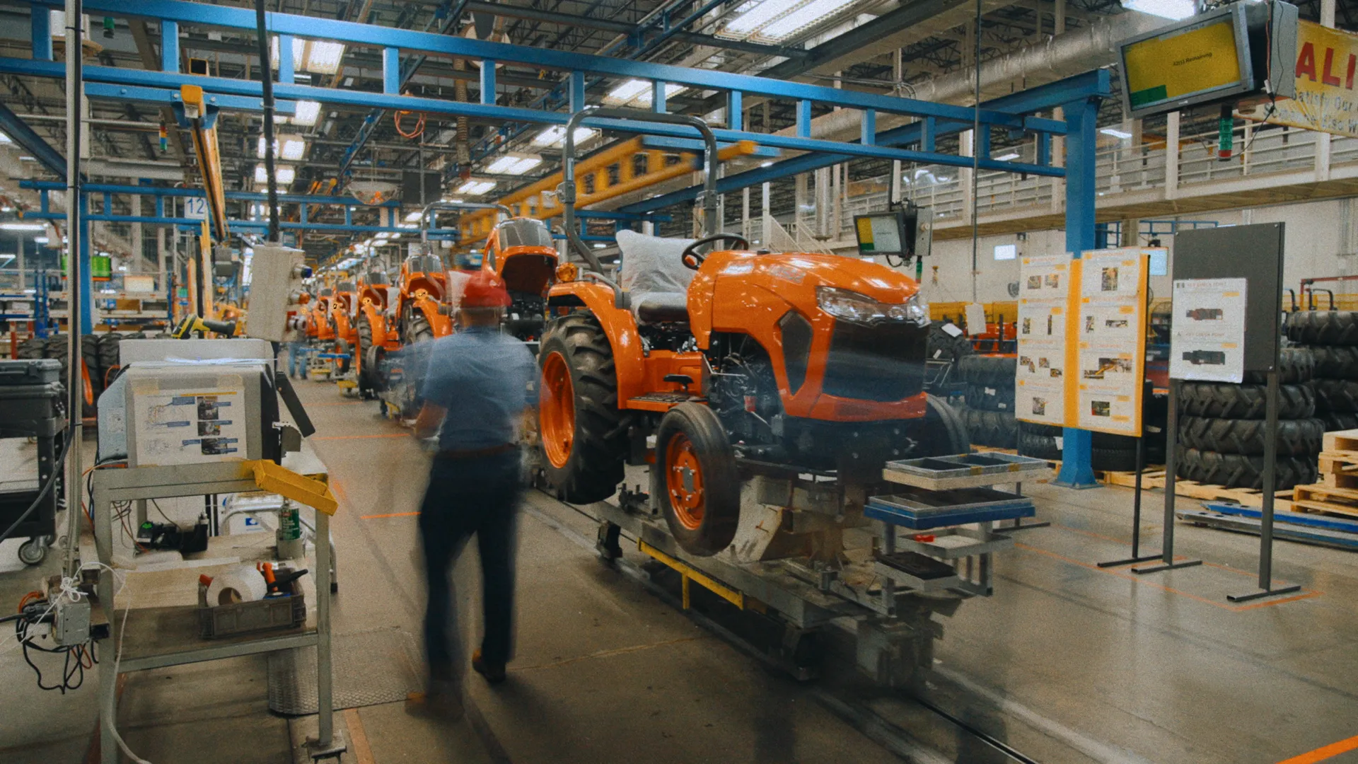 Orange Kubota tractors moving down the assembly line