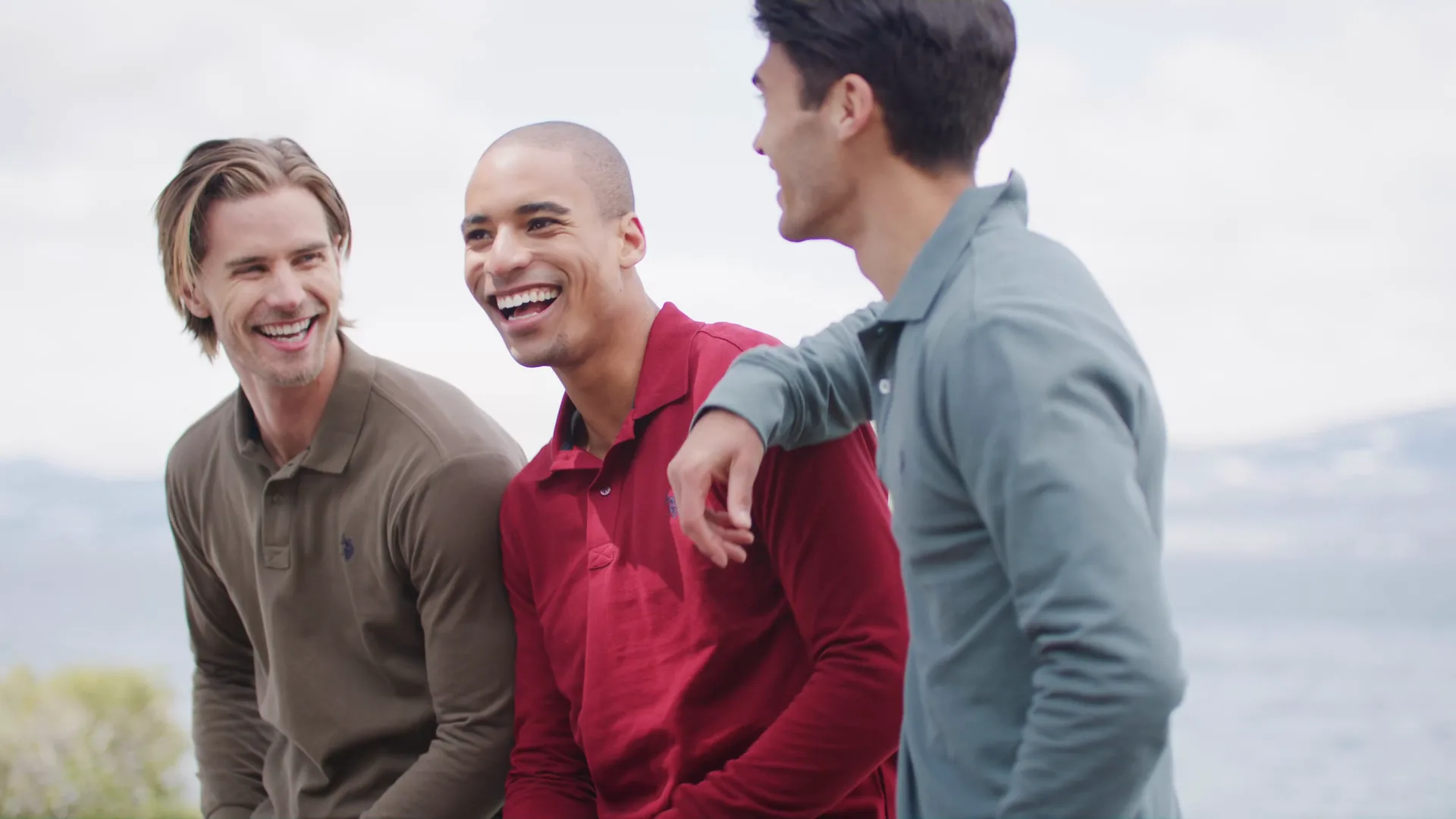 Three friends laughing together at a lakeside lookout