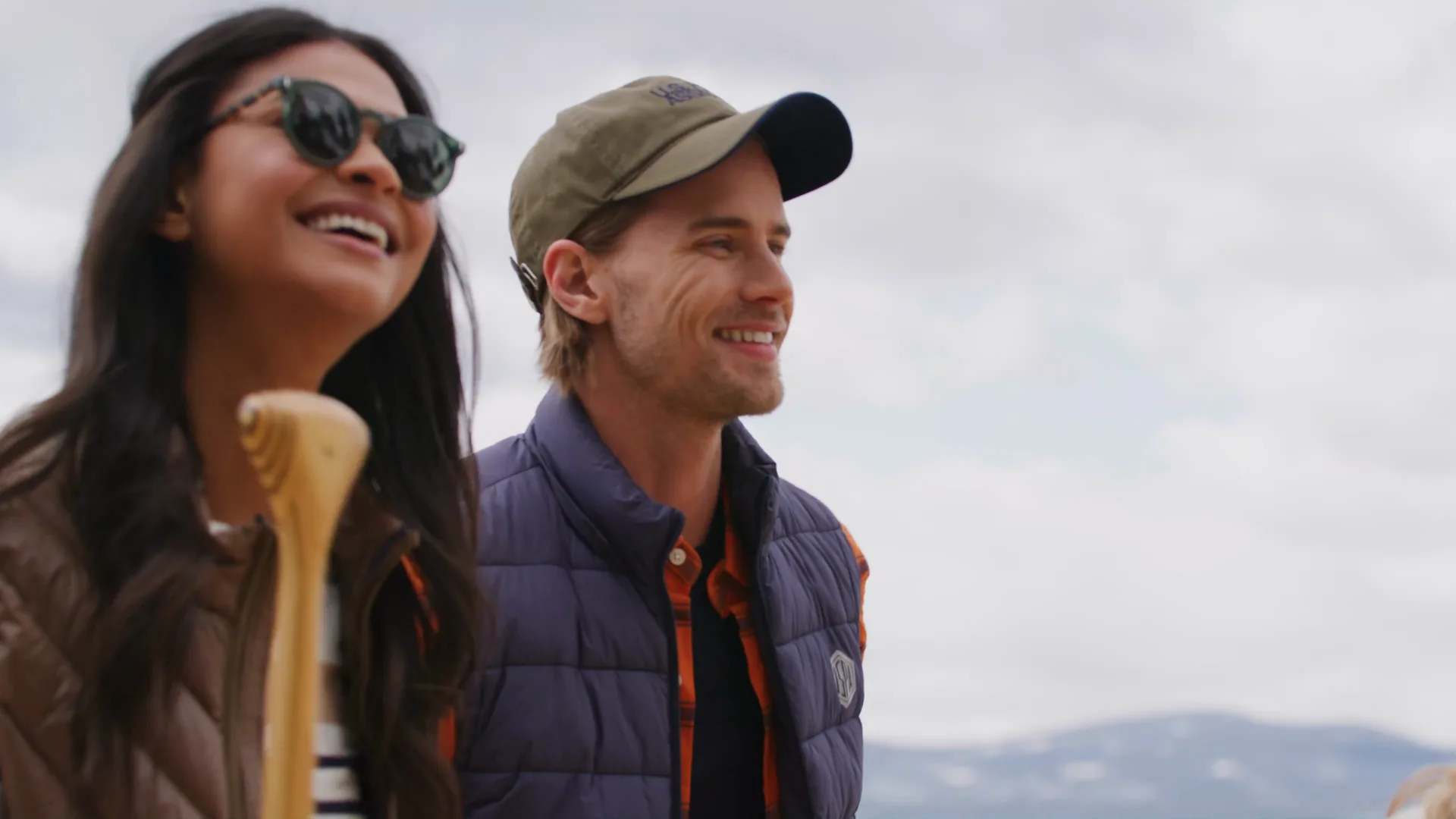 A couple laughing together on a beach under a cloudy sky