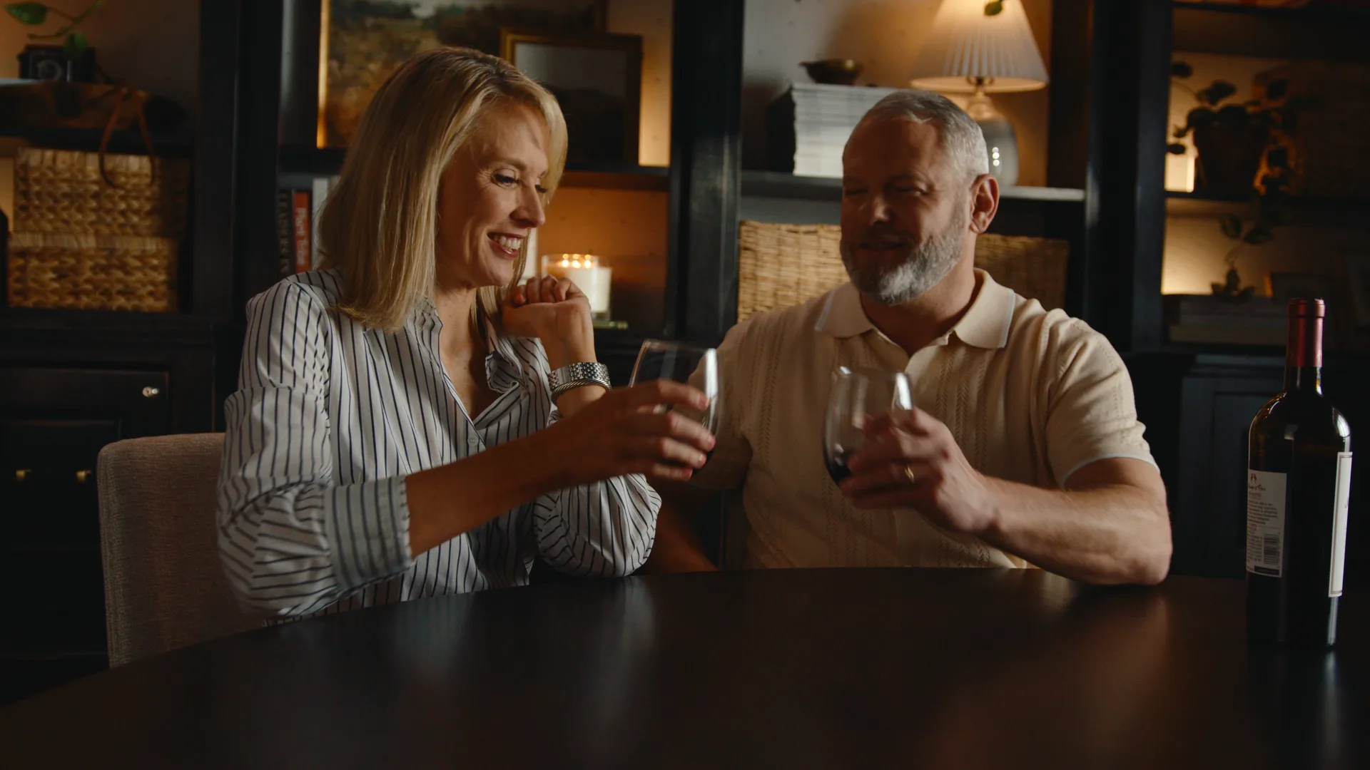 A couple clinking wine glasses at a candlelit dinner table