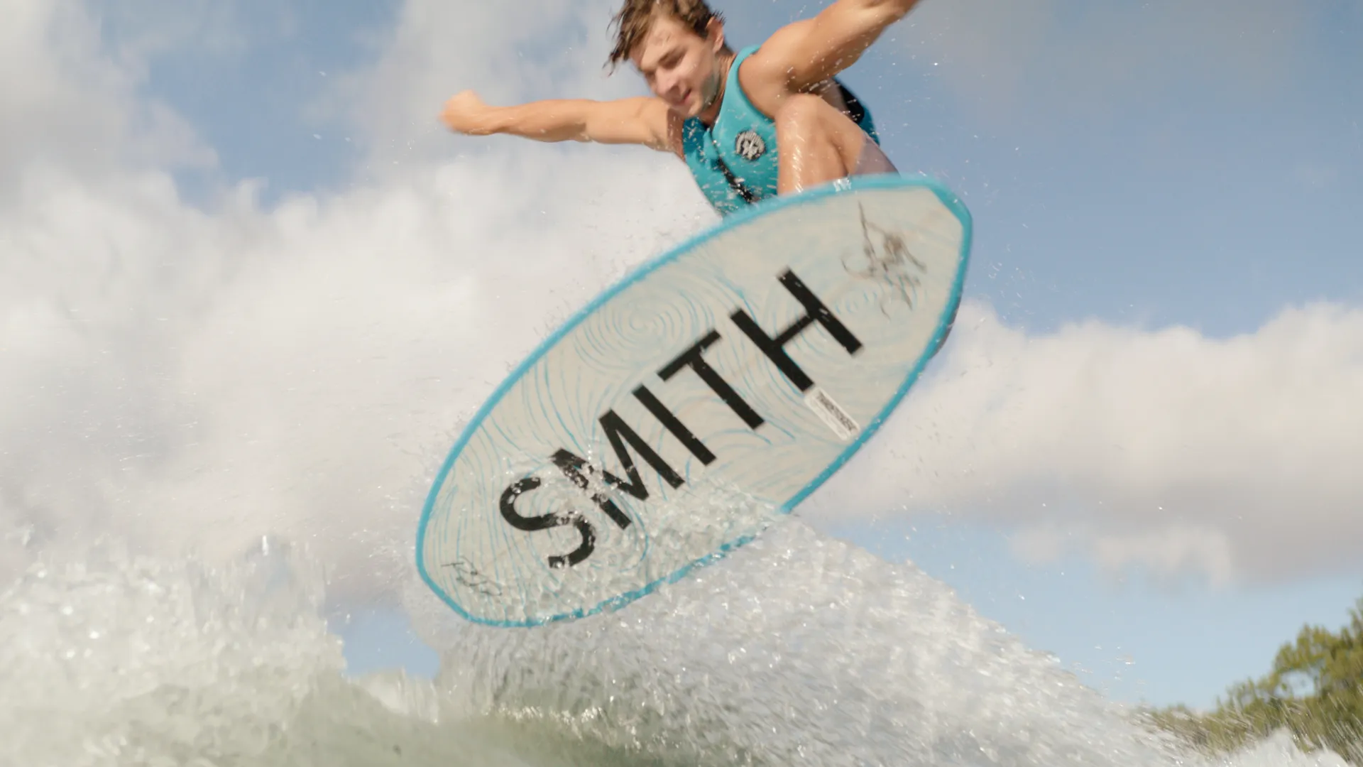 Wakesurfer mid-air from a low angle against white clouds
