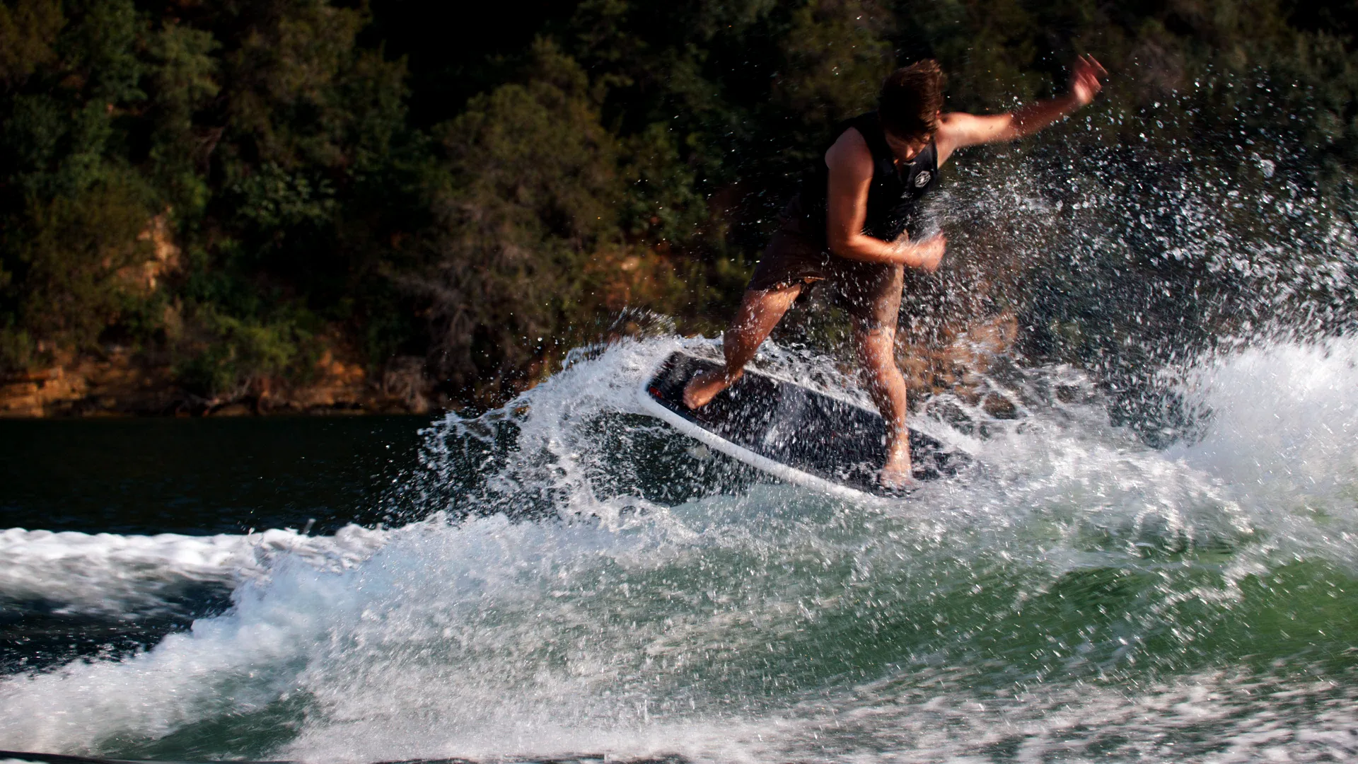 Wakesurfer carving a big spray off a green wave