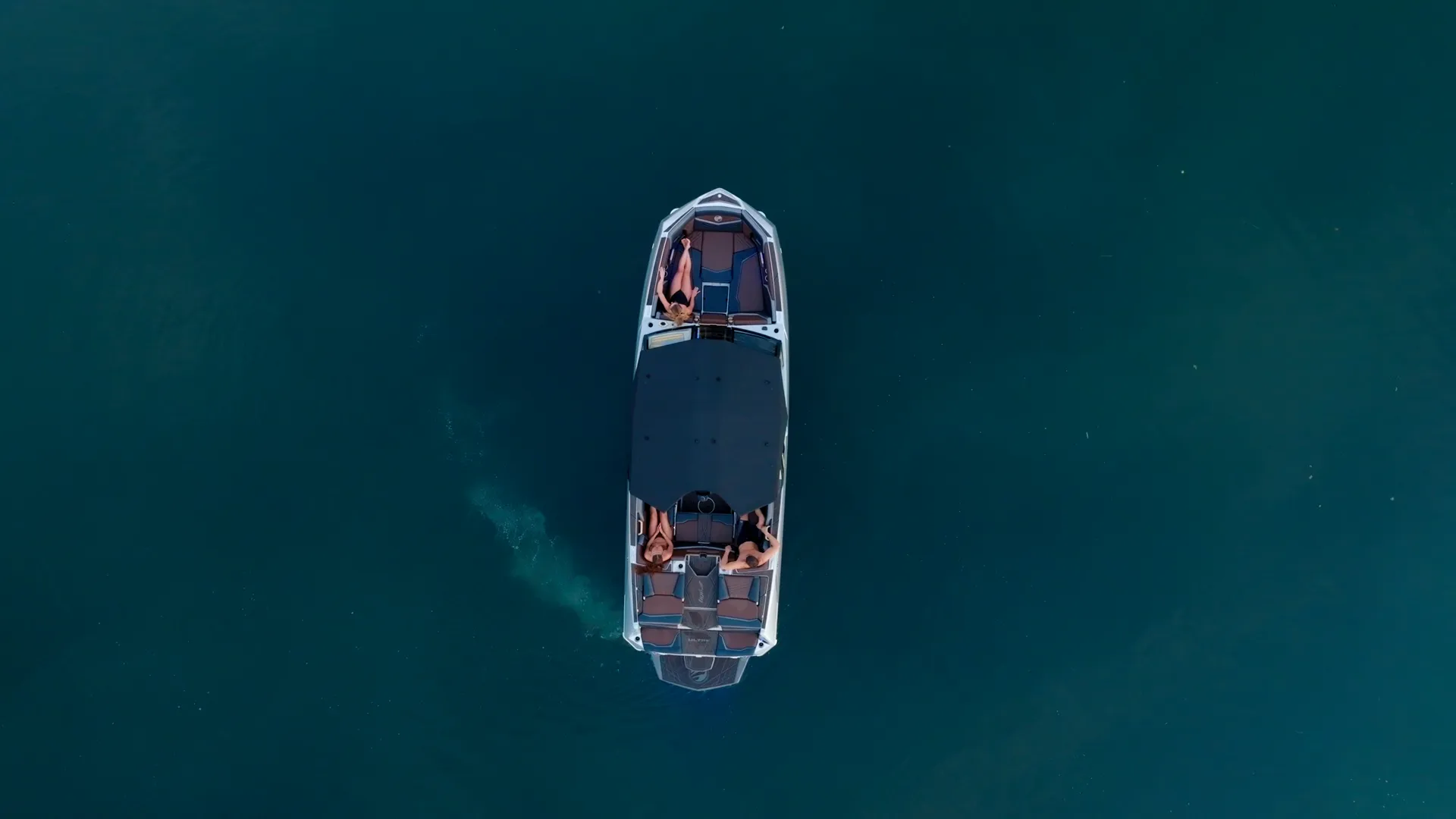 Top-down drone on a Tige boat with riders on turquoise water
