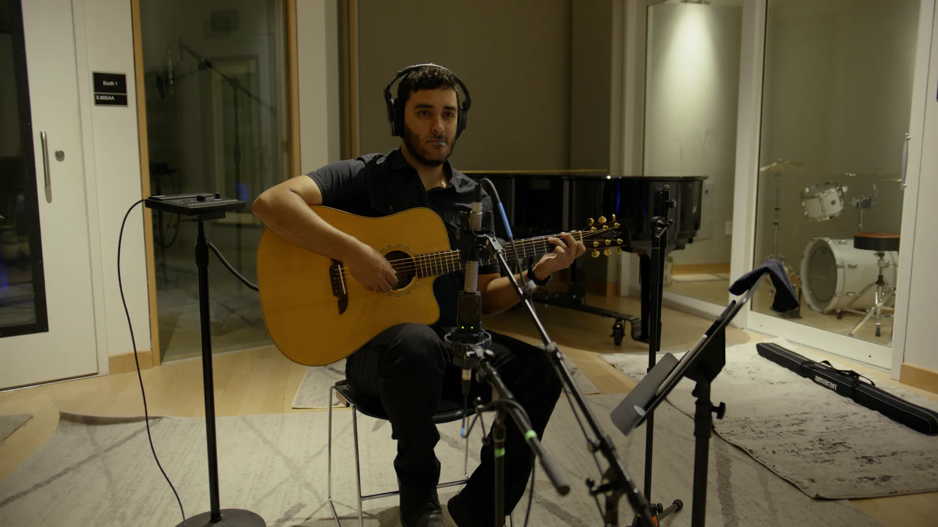 Acoustic guitarist with headphones recording in a studio live room