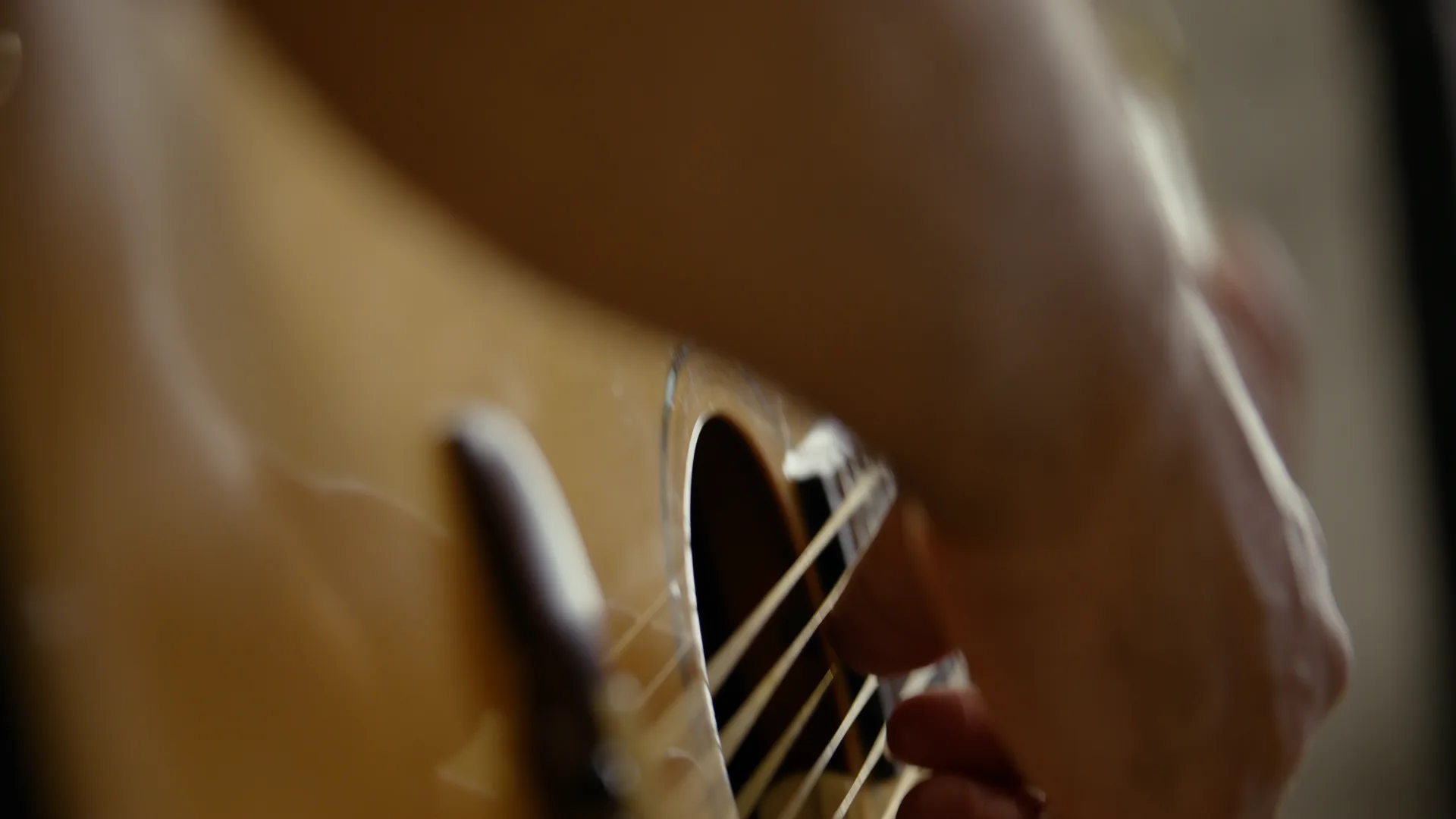 Close on a hand strumming an acoustic guitar