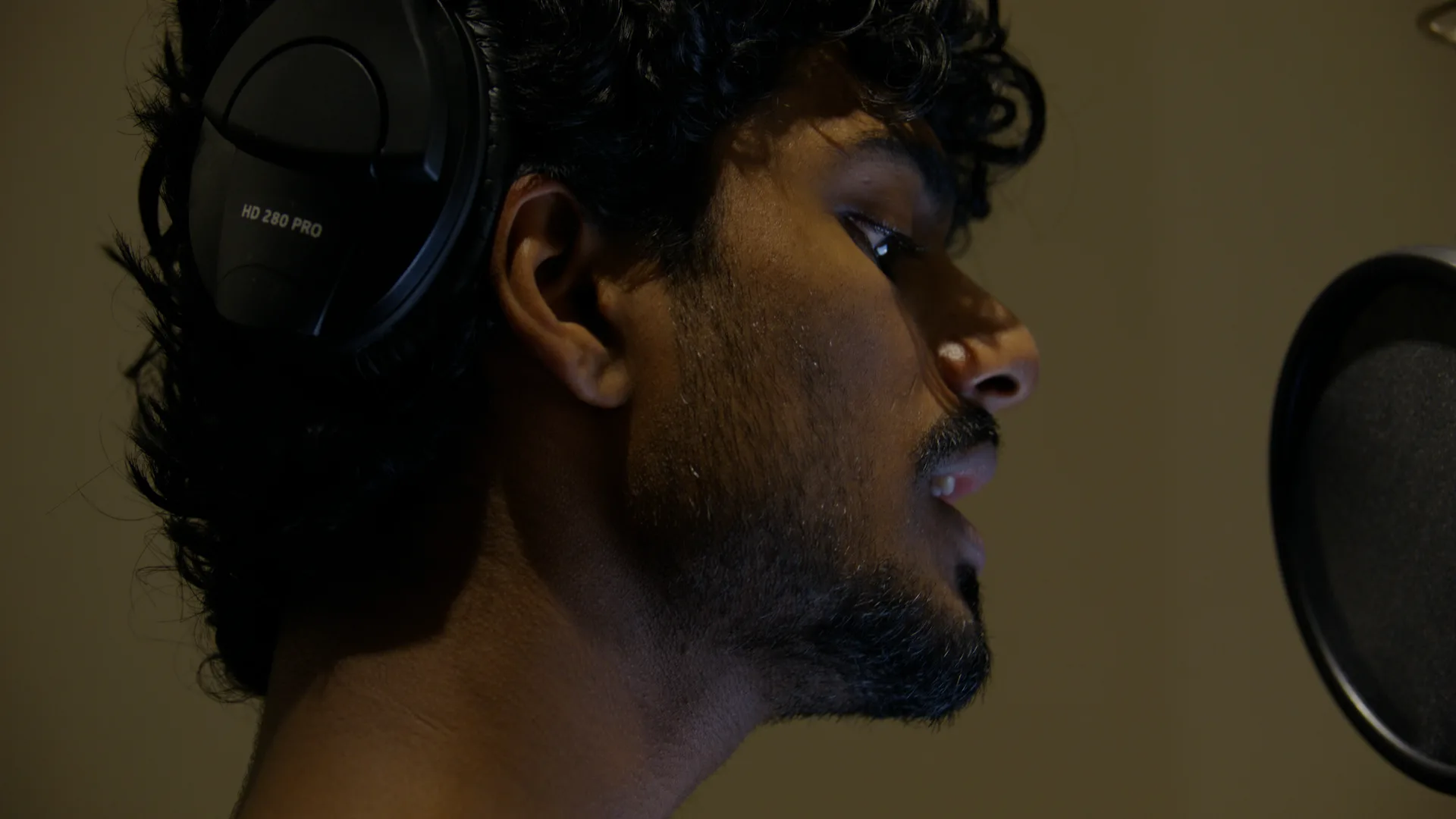 Singer in headphones in profile at the mic