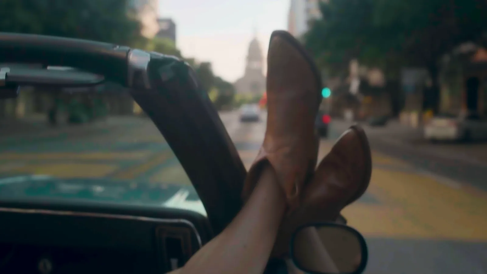 Cowboy boots on the dash of a convertible with the Capitol ahead