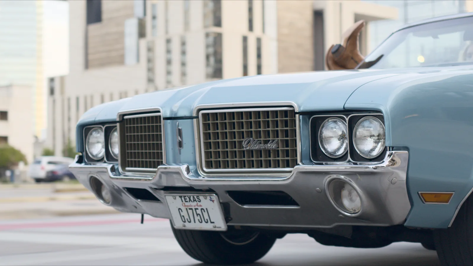 Low front tracking shot of a vintage convertible downtown