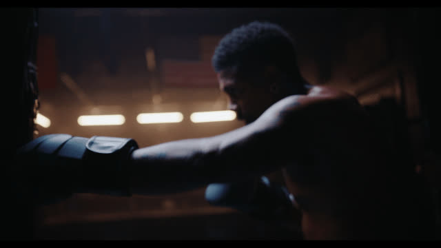 A boxer throwing a punch under a row of ring lights