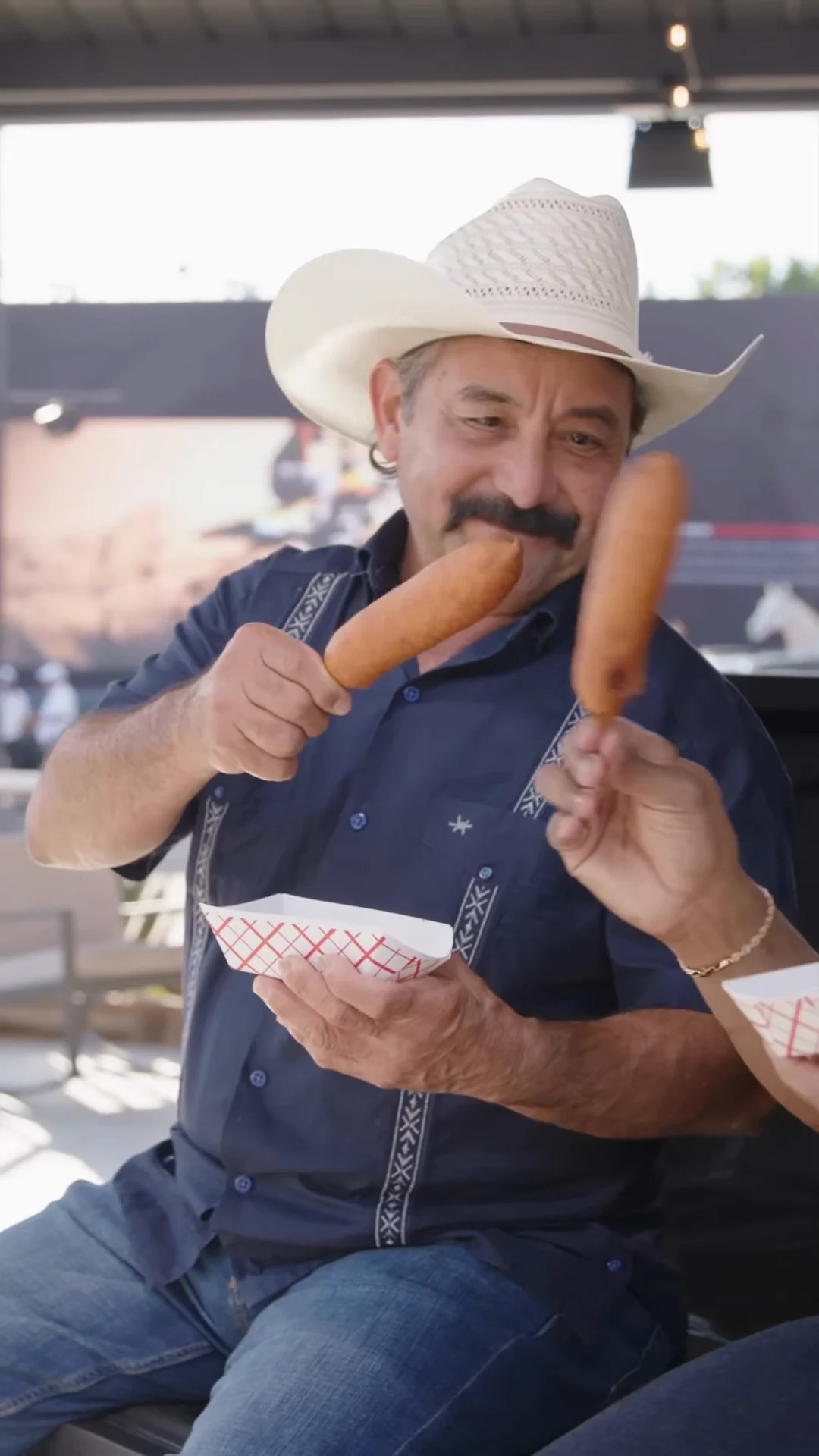 Two corny dogs raised in a toast on the tailgate