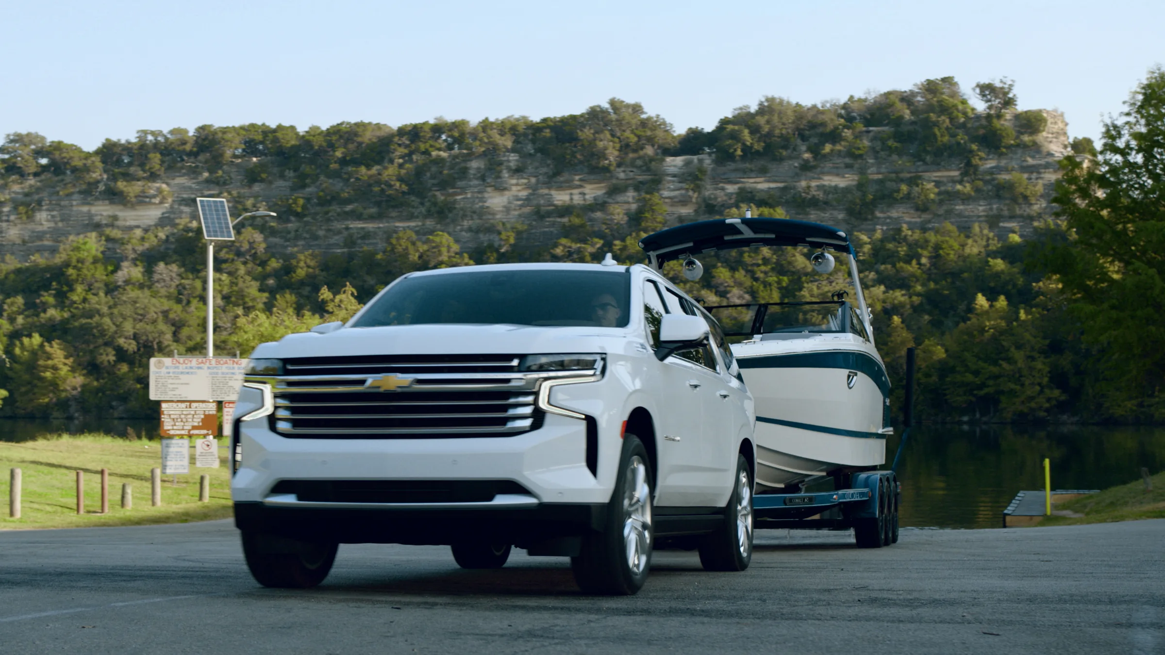 The Suburban and Cobalt at a lake boat ramp beneath a limestone bluff