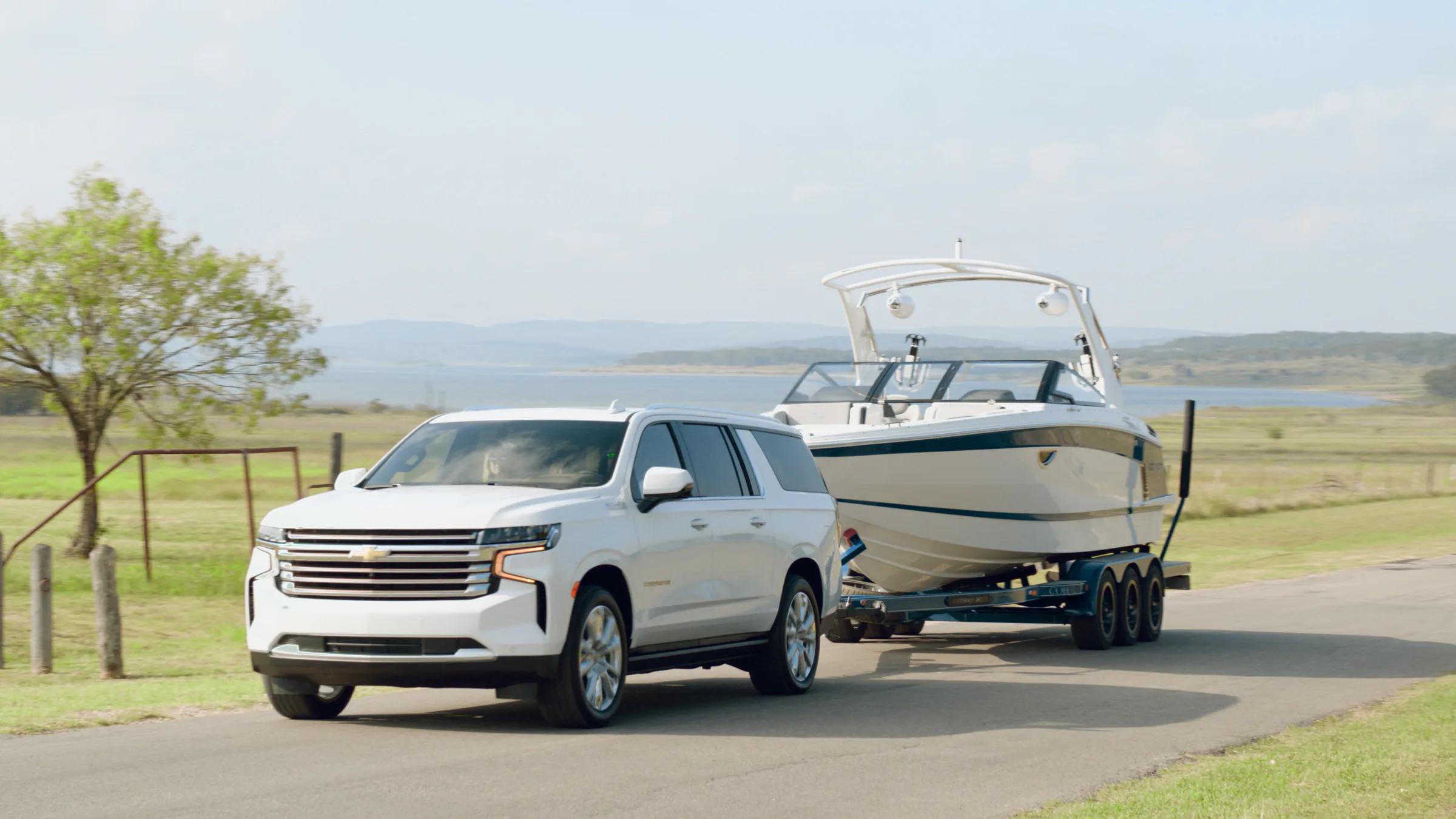 The Suburban and Cobalt on a lakeside road, open water on the horizon
