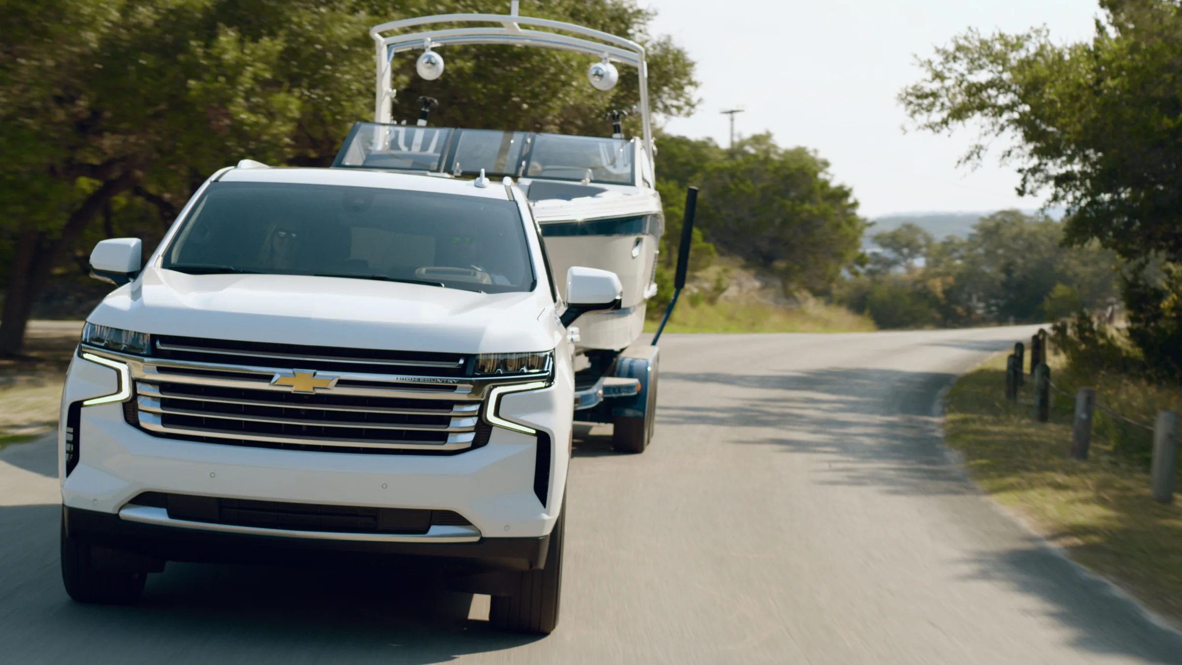 The Suburban and Cobalt on a winding park road under oaks