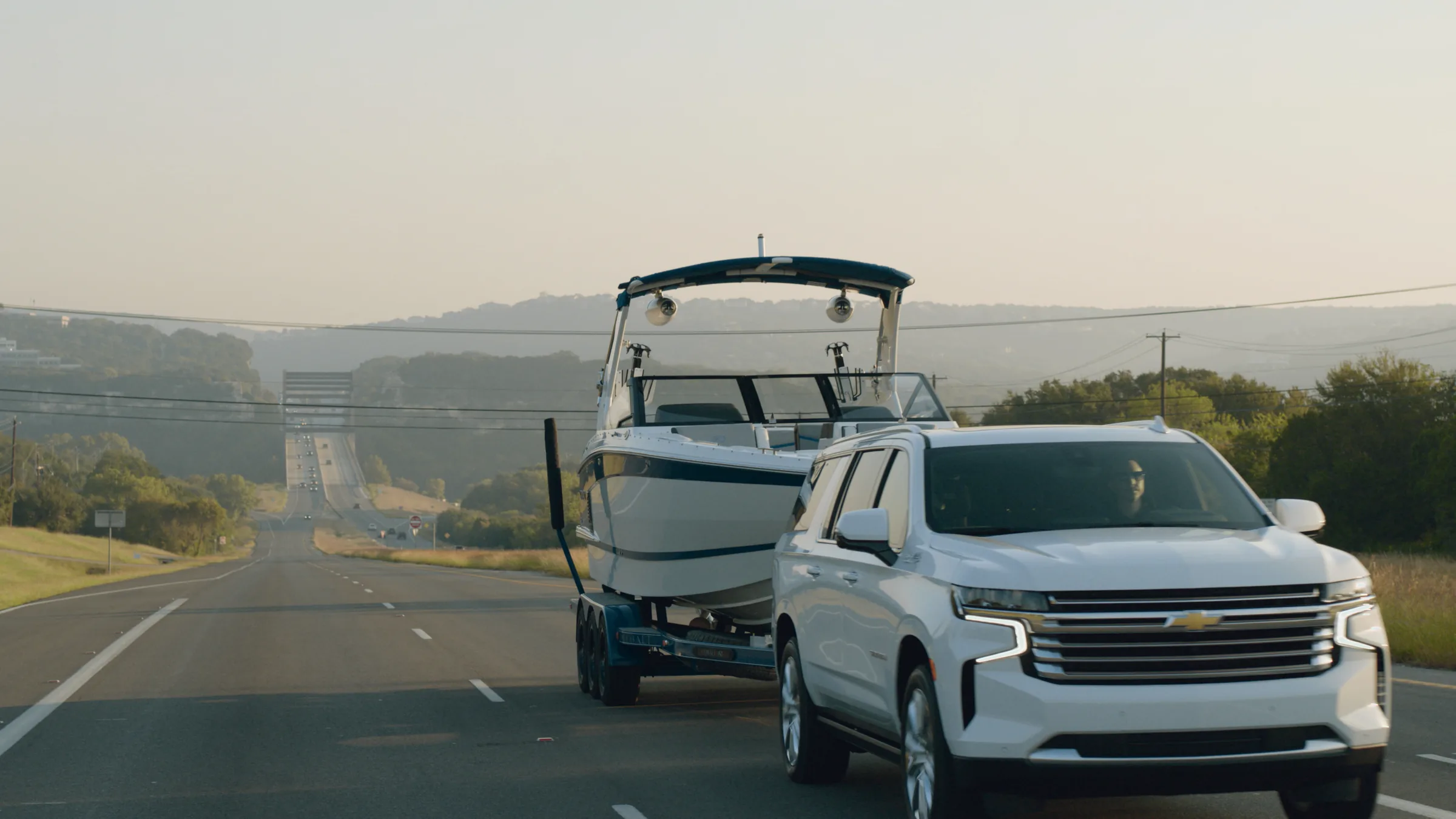 The Suburban and Cobalt on a hazy highway with the Pennybacker Bridge in the distance