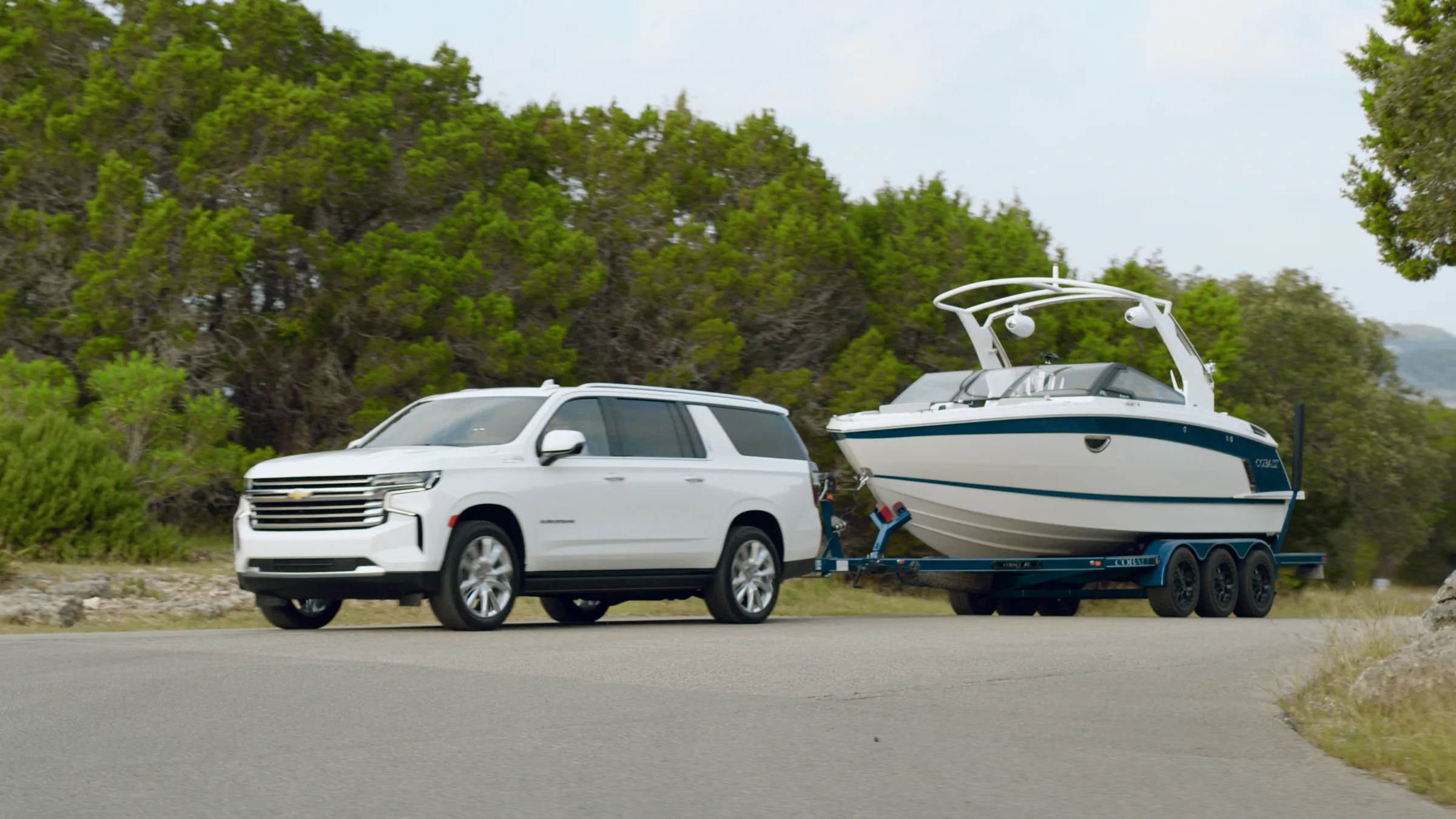 The Suburban and Cobalt in profile on a Hill Country road