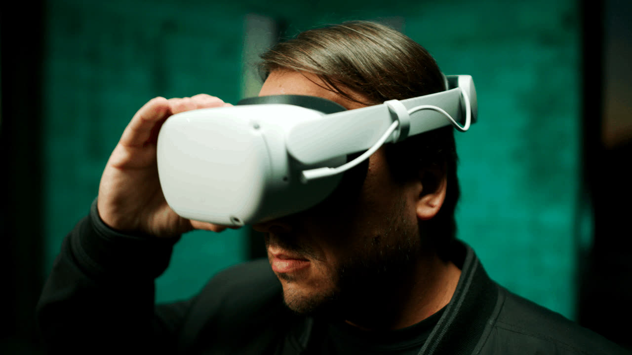 A man pulling on a VR headset in teal light