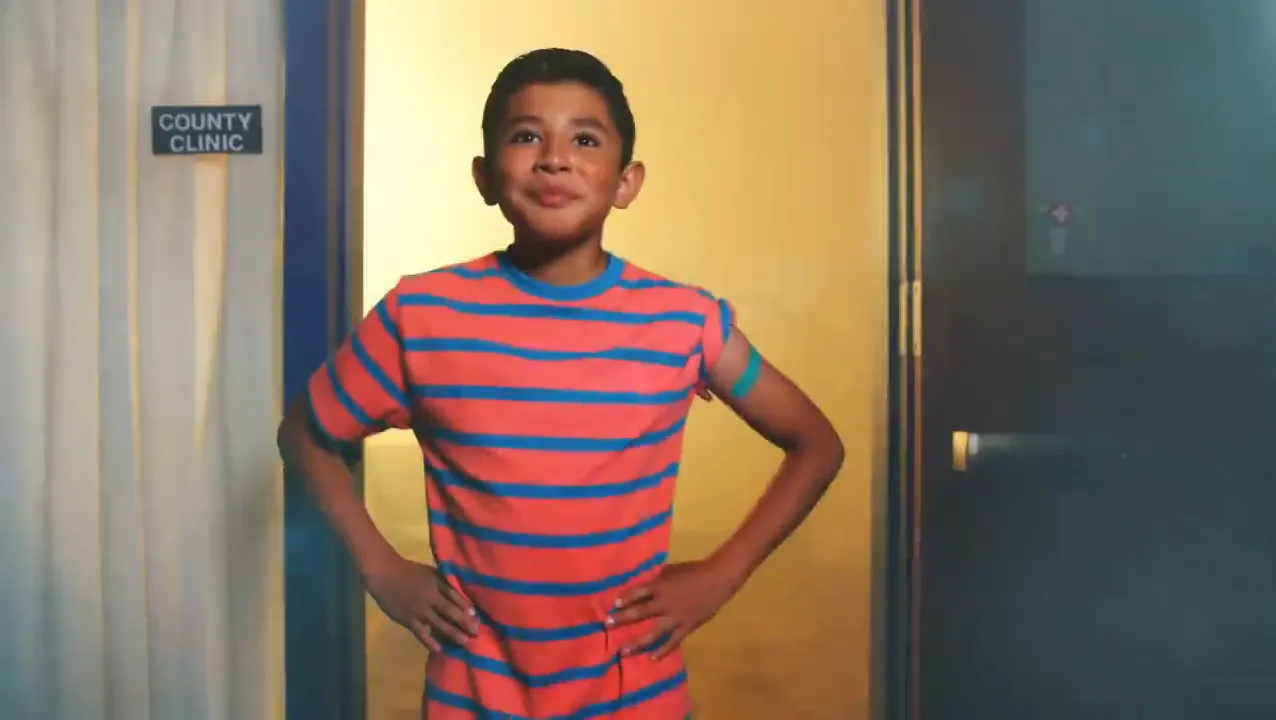 A boy in a striped shirt with his hands on his hips in a clinic doorway