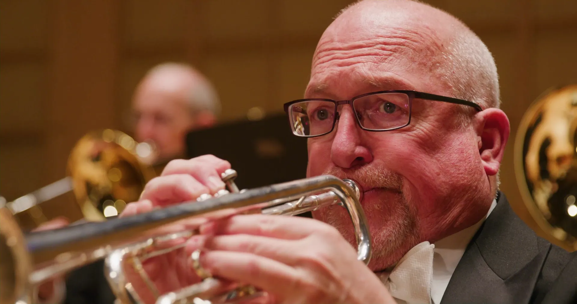 A trumpet player in glasses mid-note