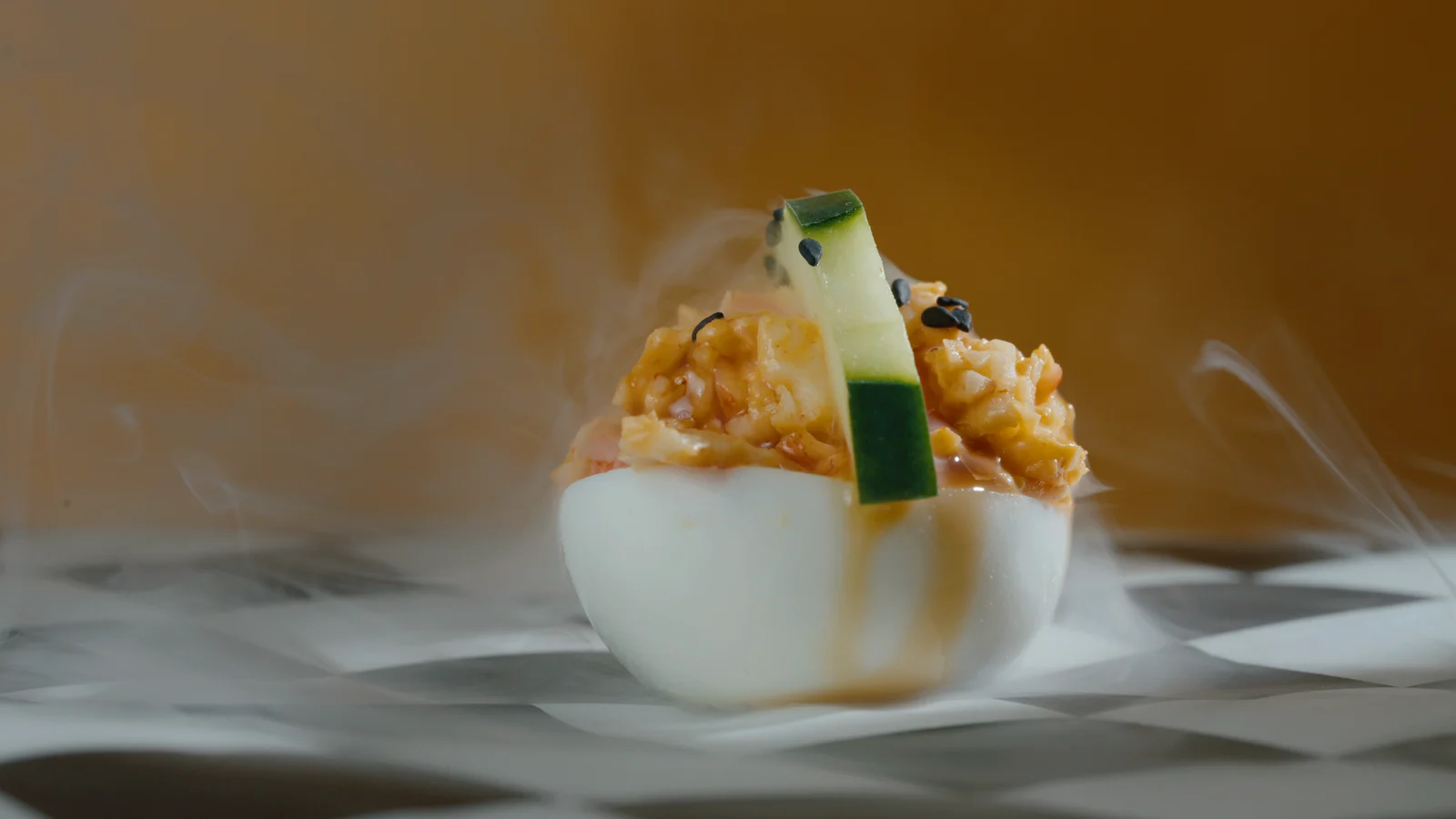 Sesame cucumber deviled egg turning as haze lifts off the checkerboard