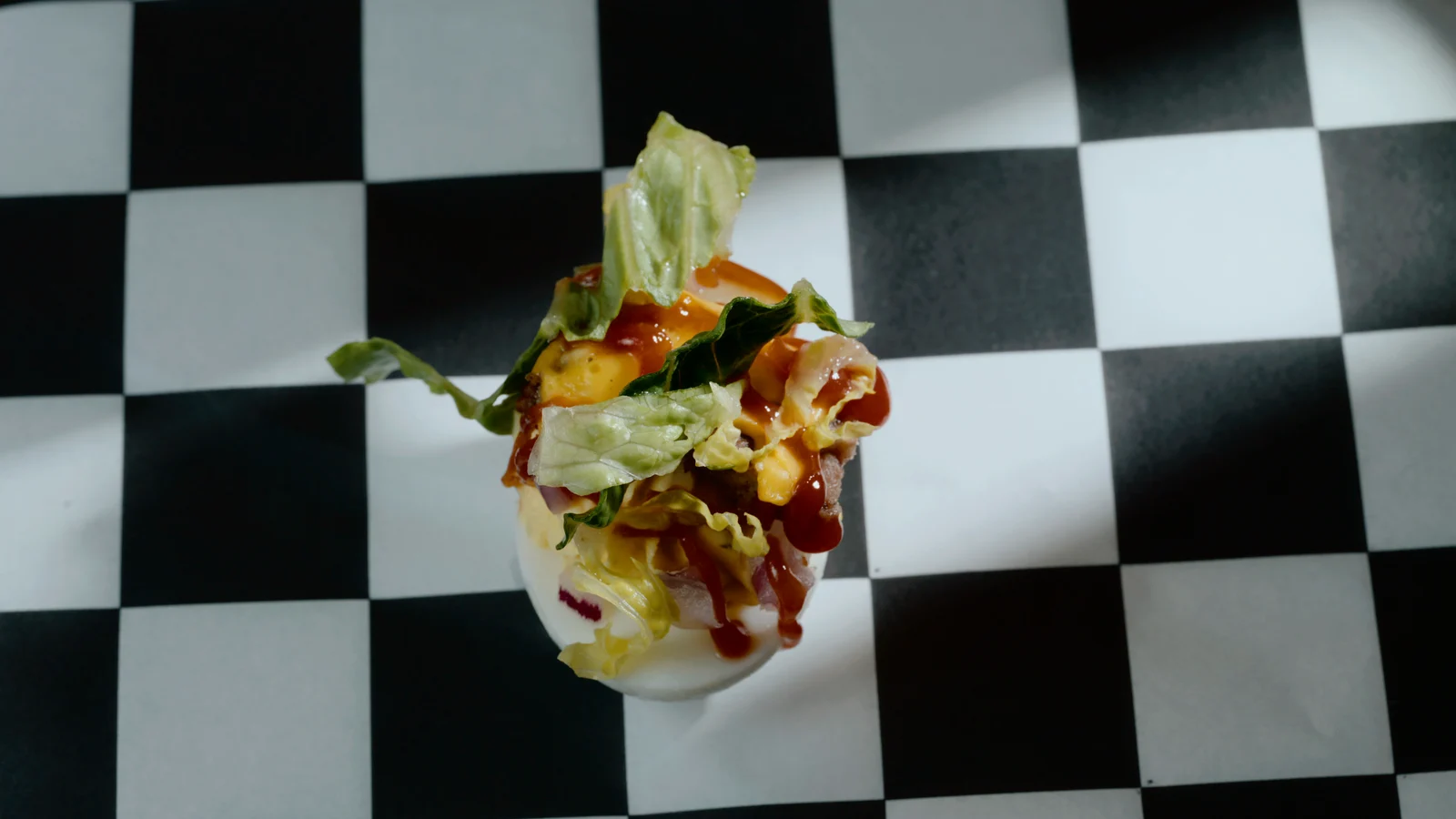 Top-down on a loaded deviled egg over a black and white checkerboard