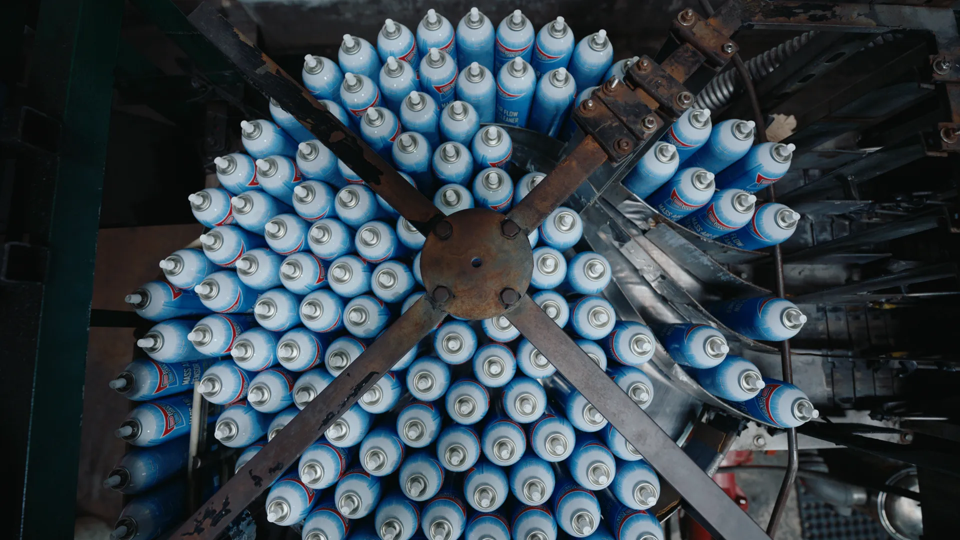 Overhead view of a rotary accumulator crowded with blue and white aerosol cans