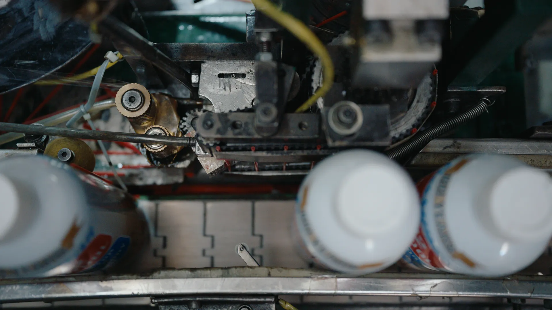 Top view of white-capped bottles passing through a labeling machine