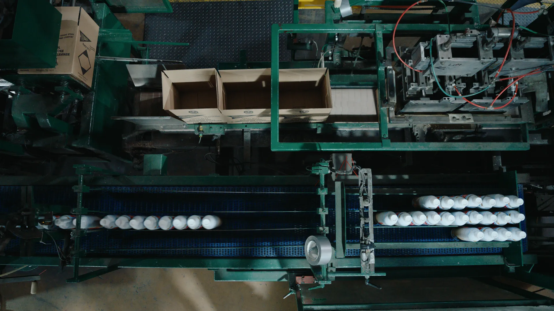 Overhead view of an automated packing line moving cans and boxes