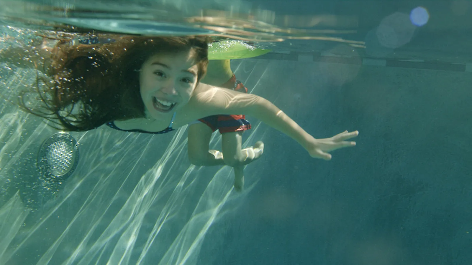 Underwater shot of a girl swimming in a sunlit pool