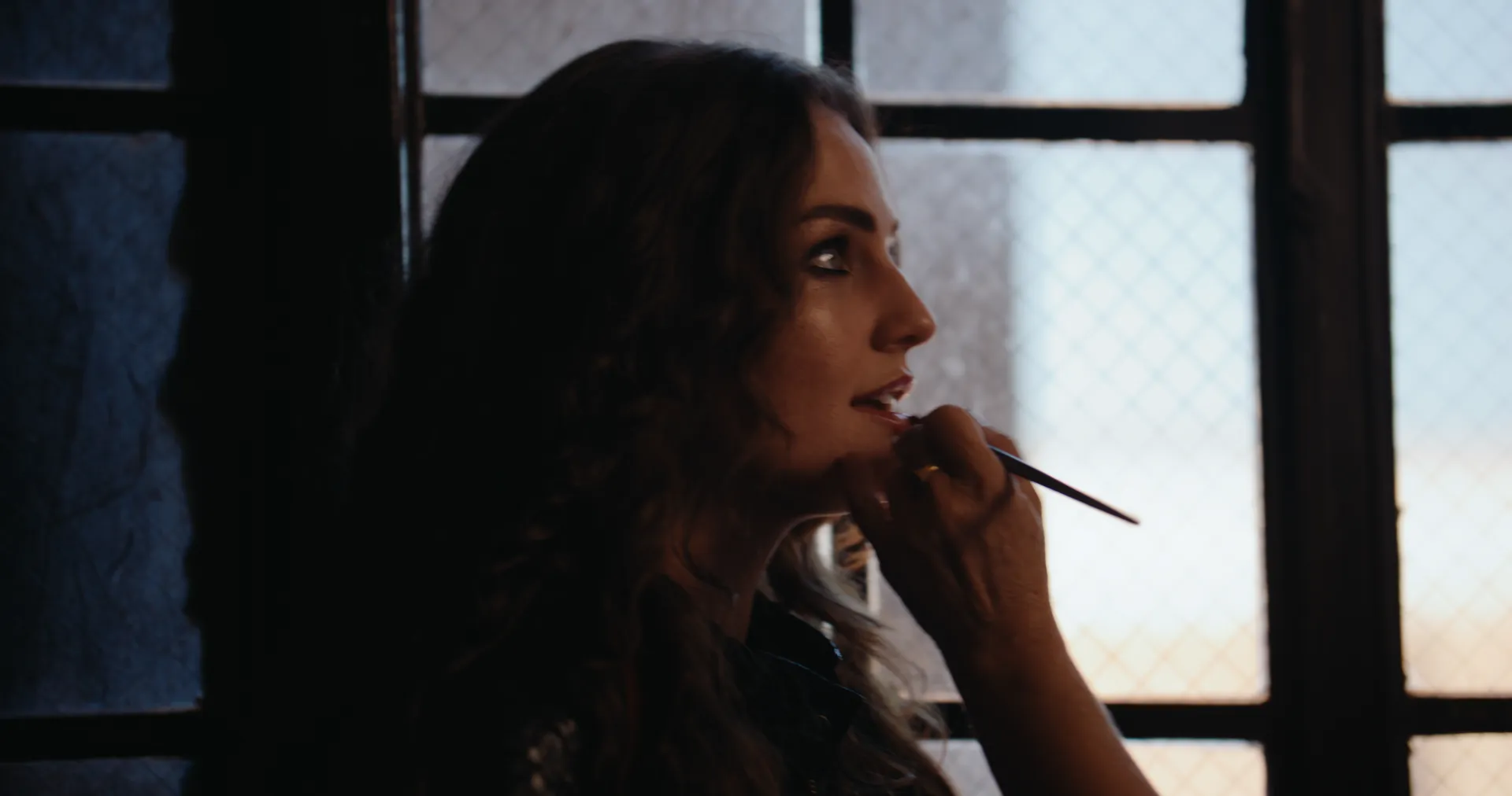 Khasty touching up her lipstick by the window