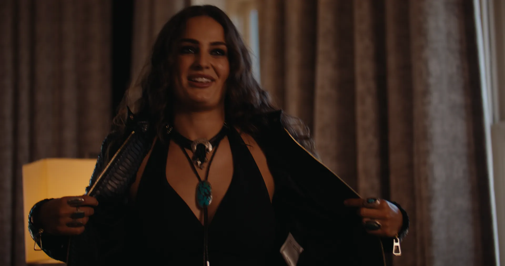 Khasty opening her jacket in a hotel suite