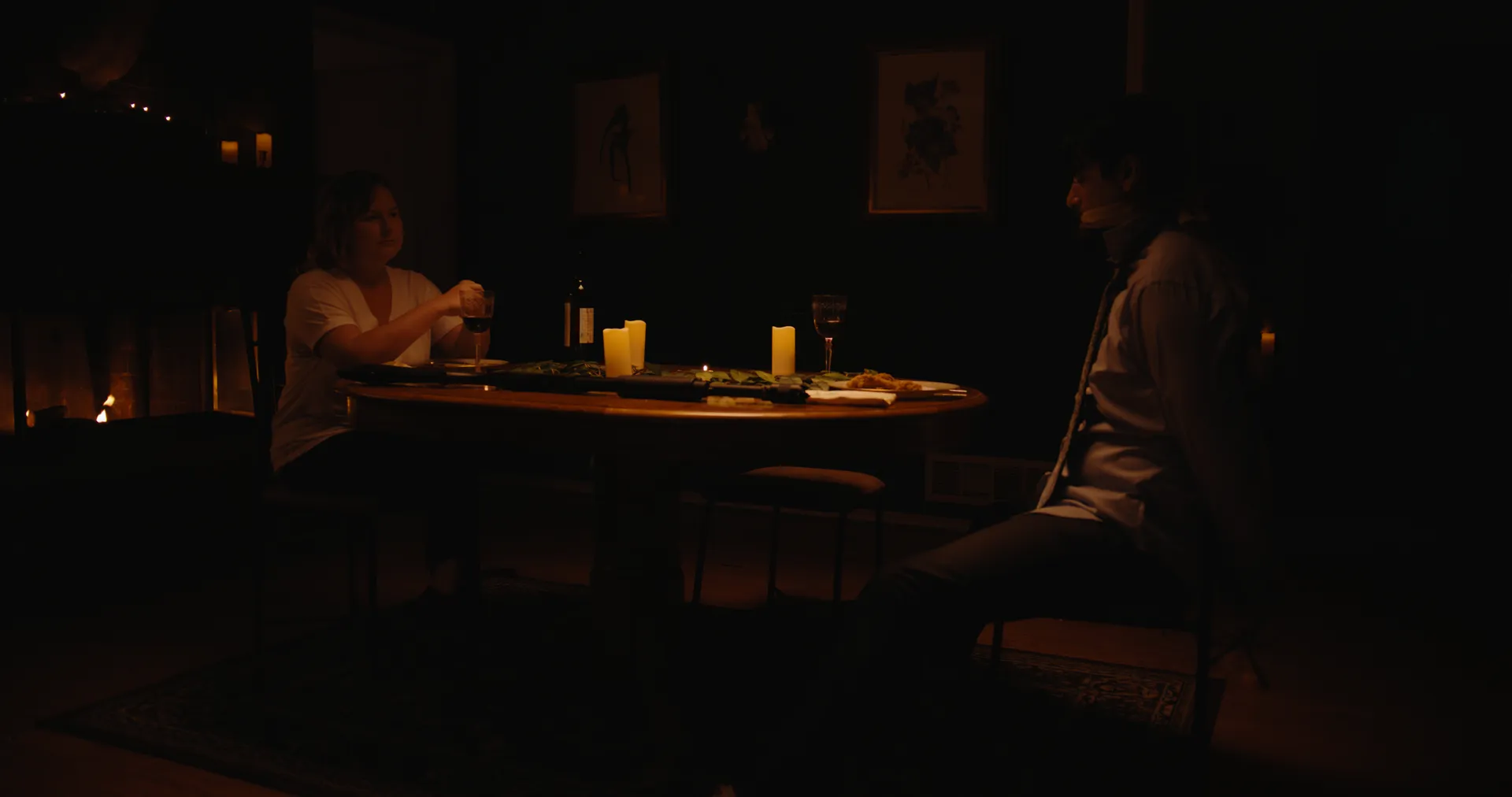 Two people at a candlelit dinner table in a dark room