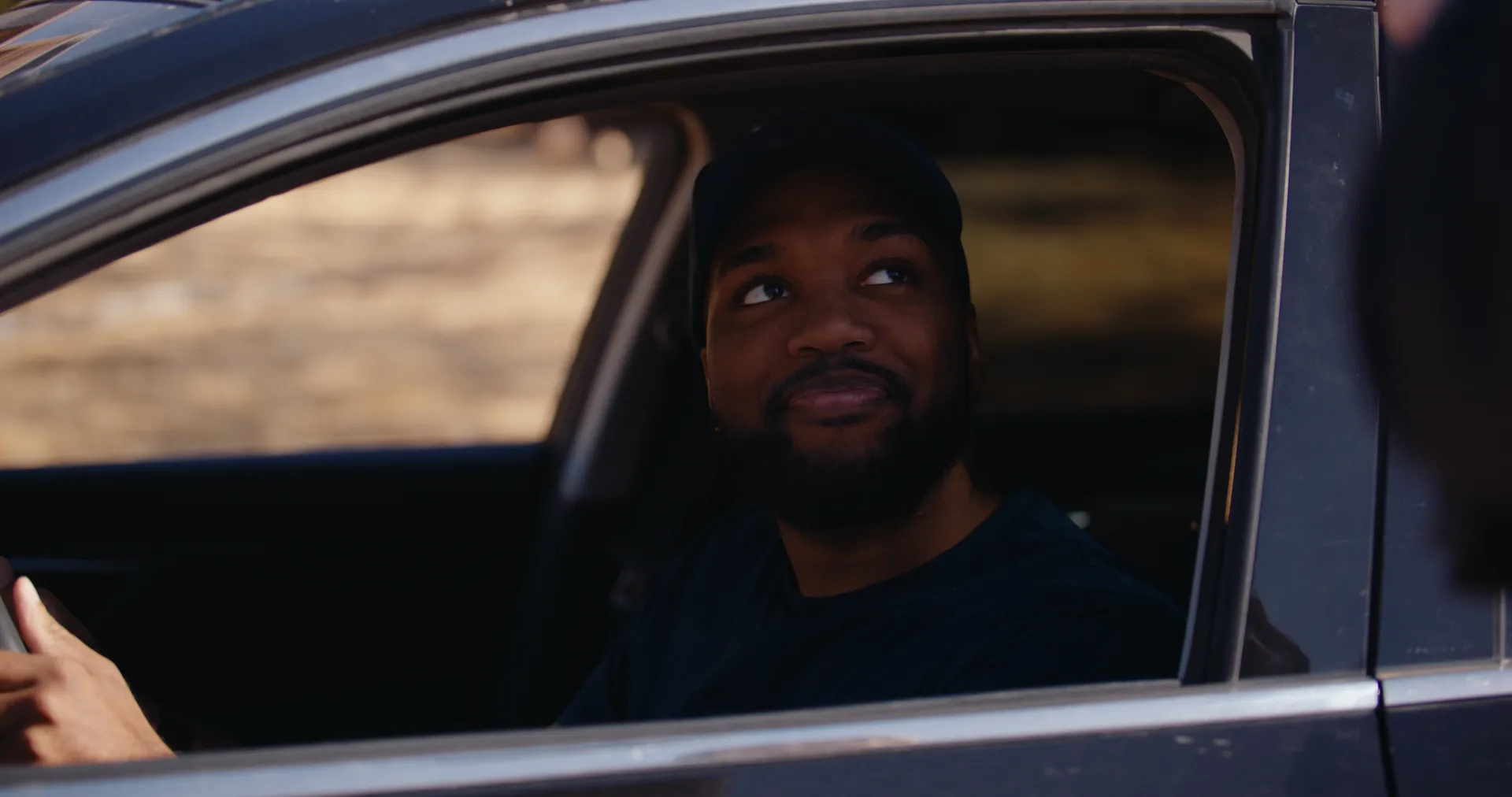 A man smiling from the driver’s seat of a car