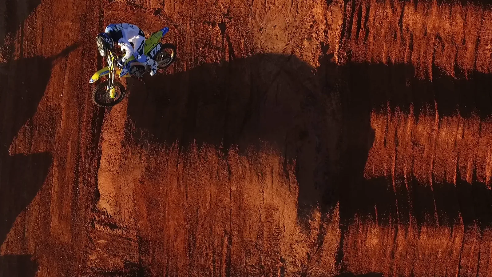 Rider whipping a jump over a dirt hill at sunset
