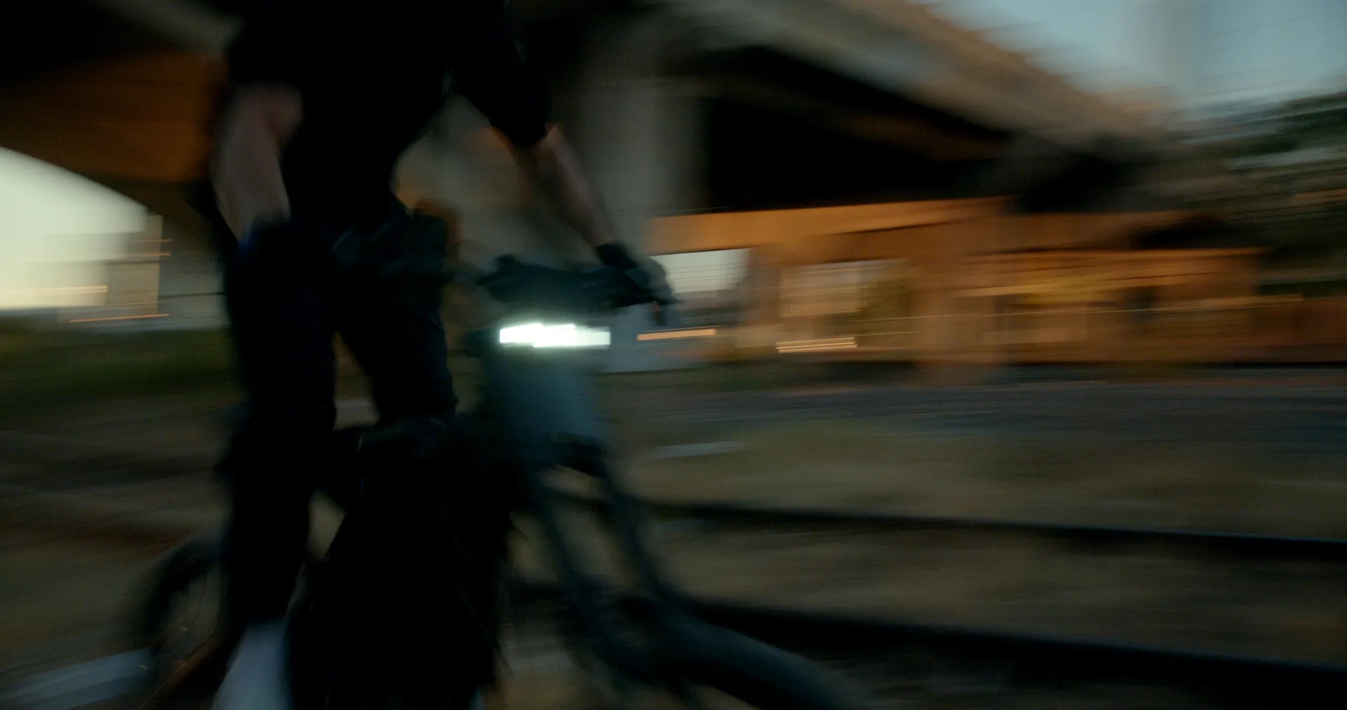 A rider speeding past on an electric bike, the bridge blurred behind