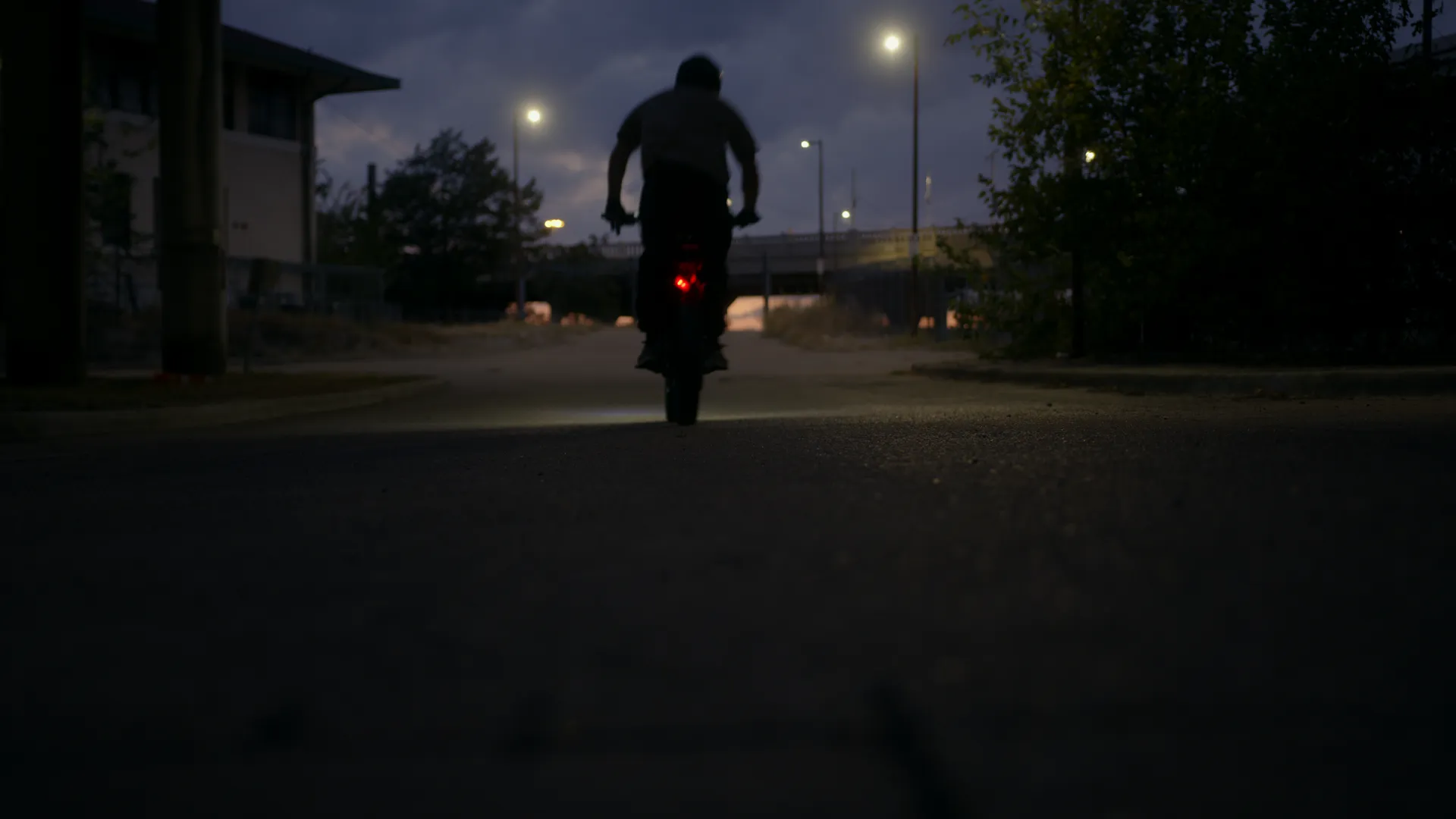A rider heading away down a street under the lights at night