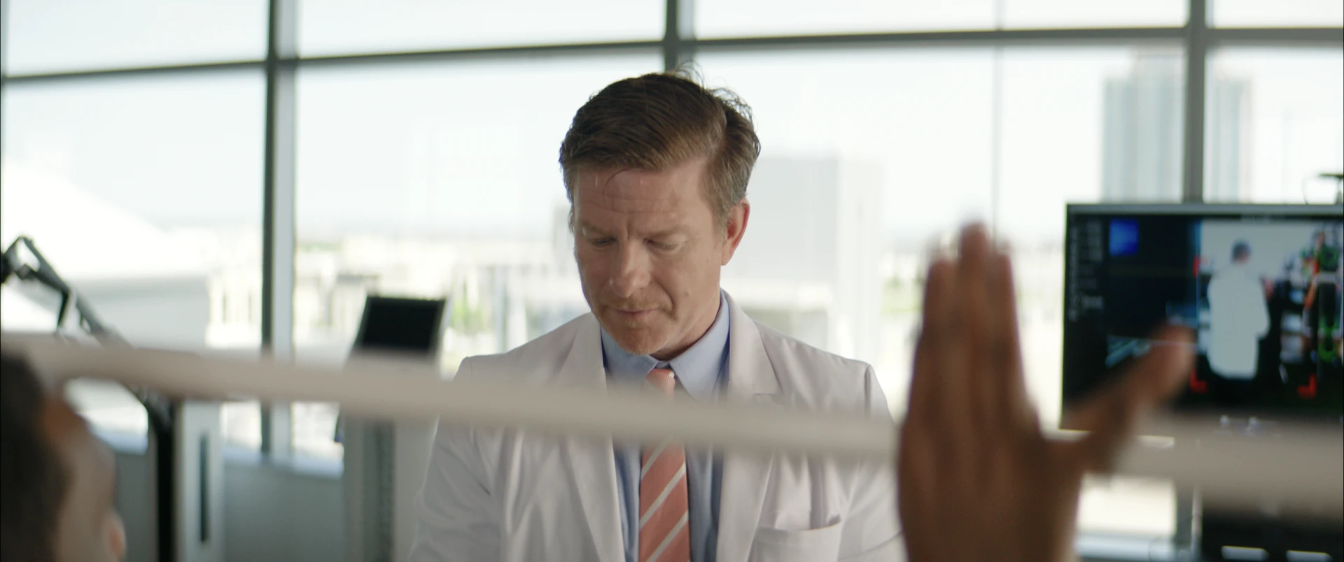 A doctor watching his patient's dowel stretch, the patient's hand soft in the foreground