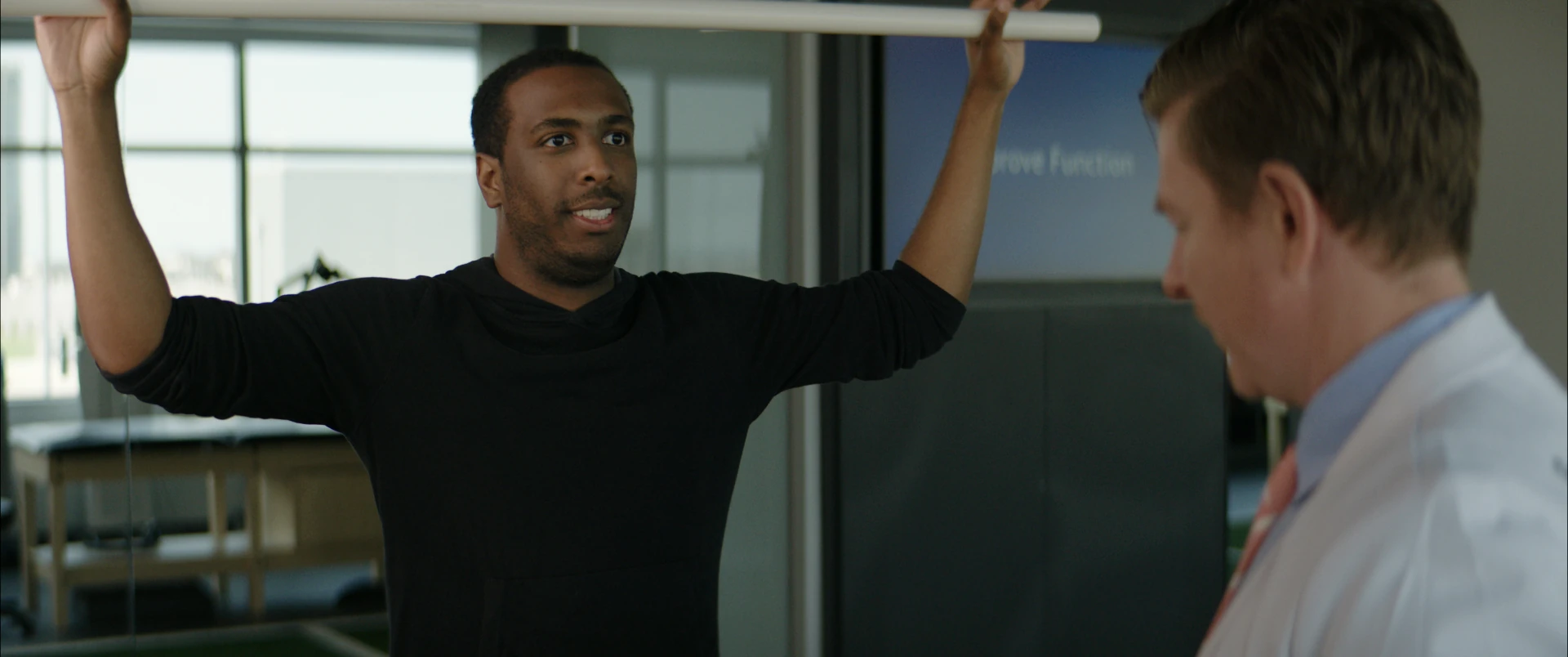 A patient raising a dowel overhead during a mobility assessment