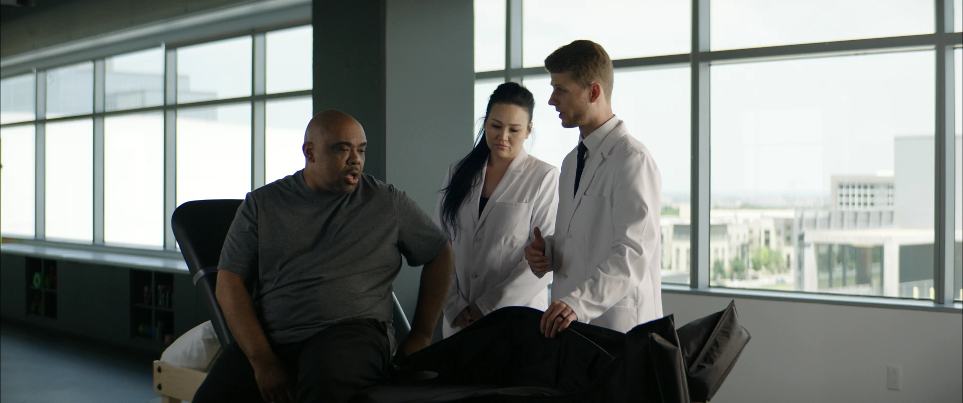 A patient talking with two clinicians beside the recovery chairs