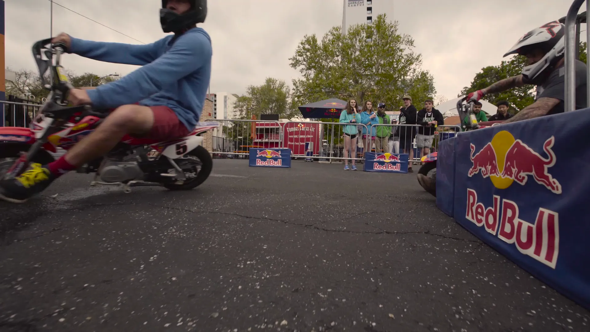 A rider on a mini bike skimming past a Red Bull barrier, shot low