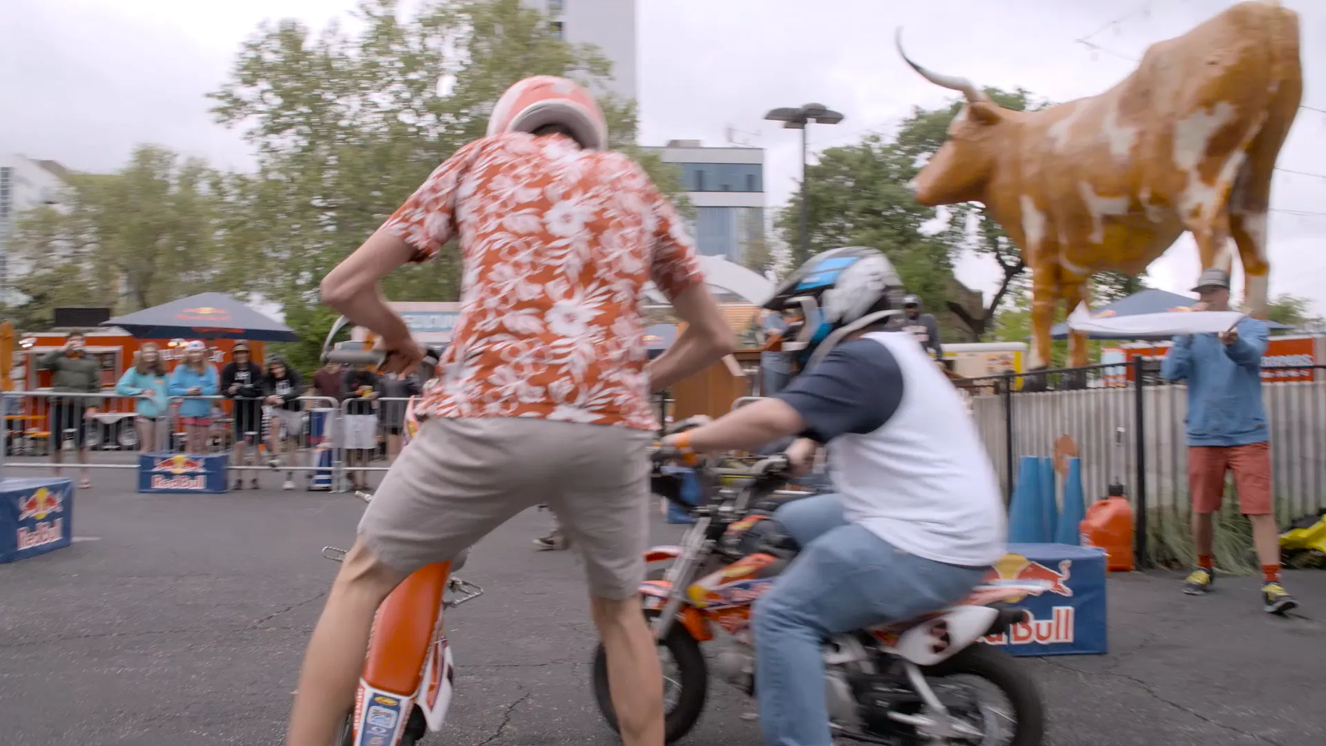 Riders on mini bikes in front of a longhorn statue
