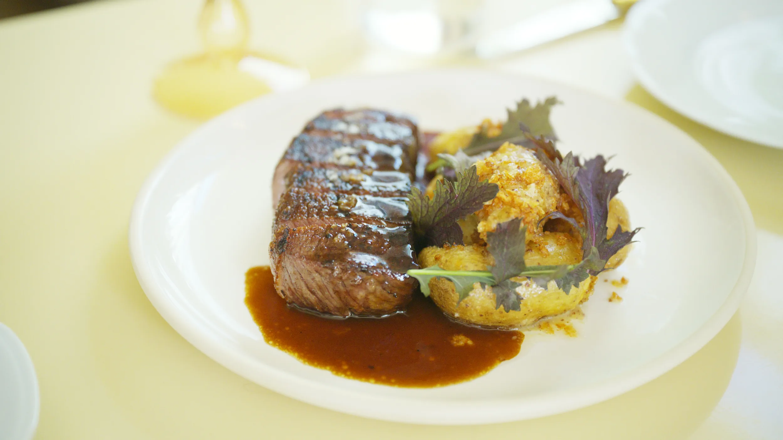 Plated wagyu strip with jus, crispy potato, and purple shiso