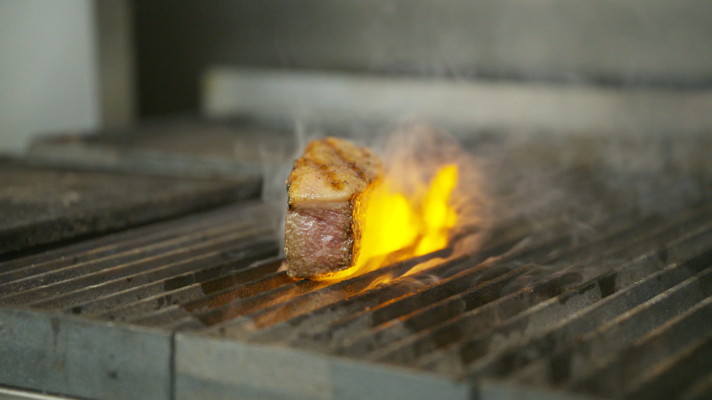 Grill-marked strip with a flame rising beside it on the grill