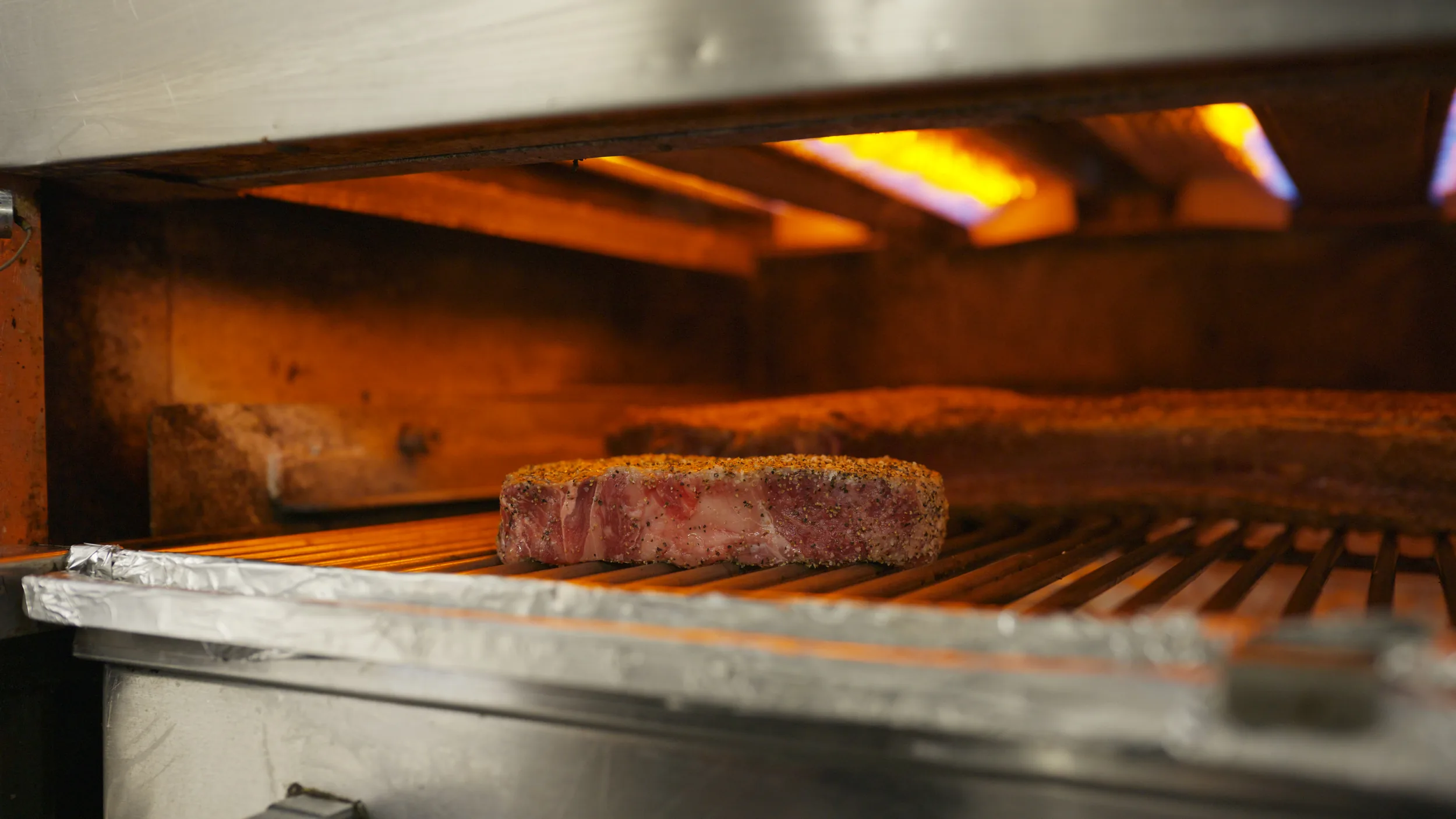 Seasoned strip under the glowing burners of a salamander