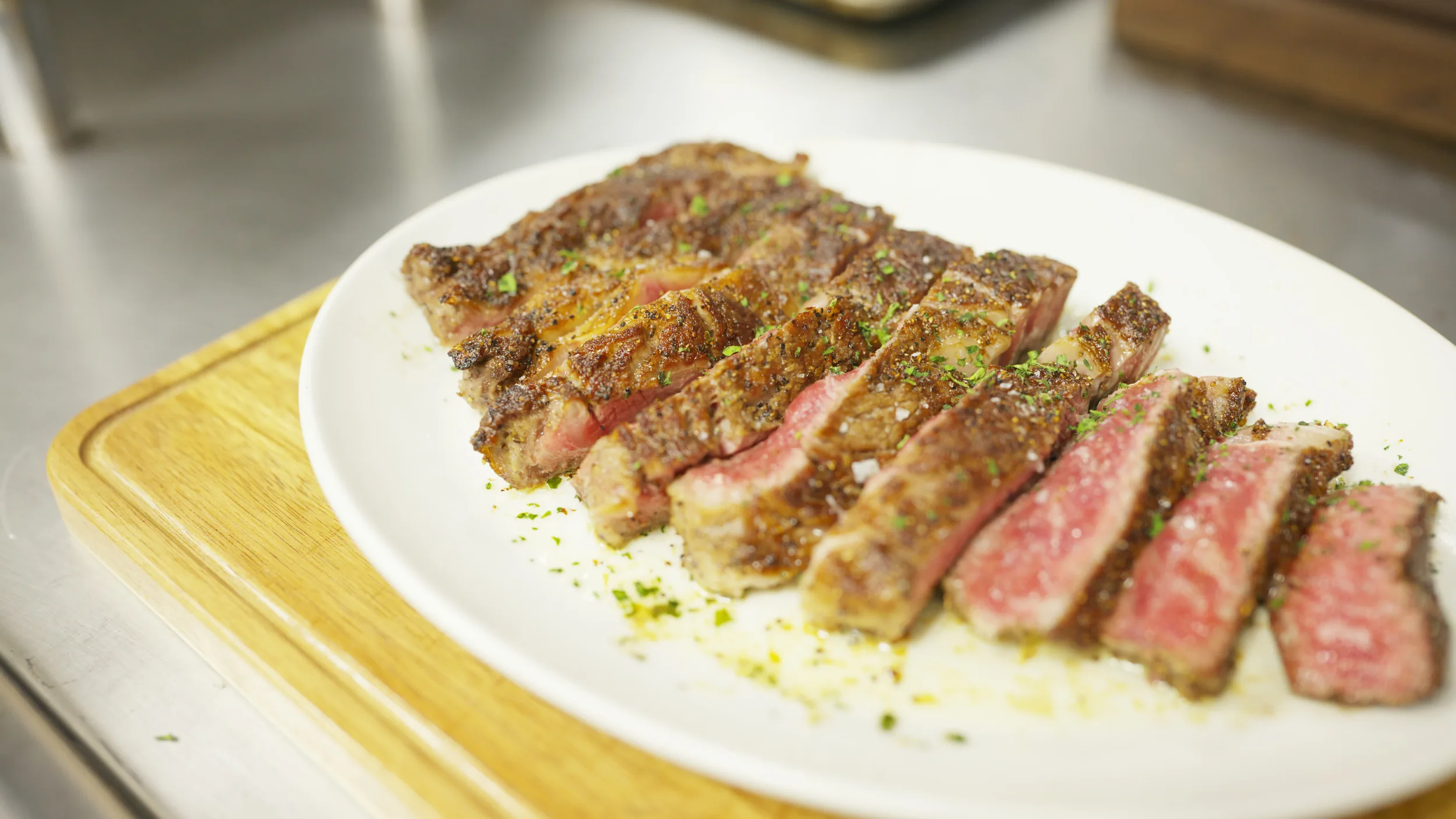 Sliced medium-rare strip on a white plate over a Senku board